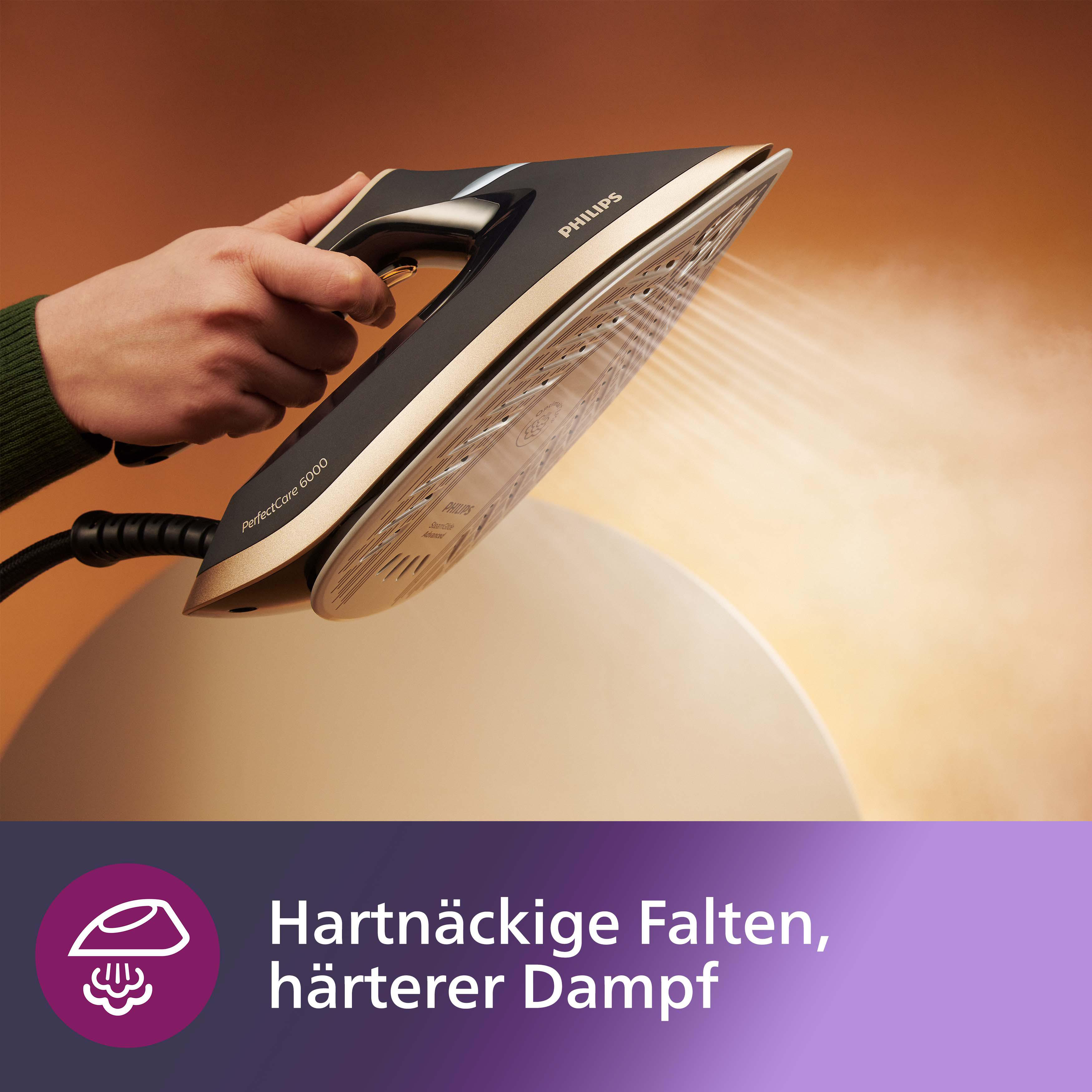 Ein schwarzes und goldenes Bügeleisen im Gebrauch, das mit weißem Dampf dampft, mit Text in der unteren Ecke.