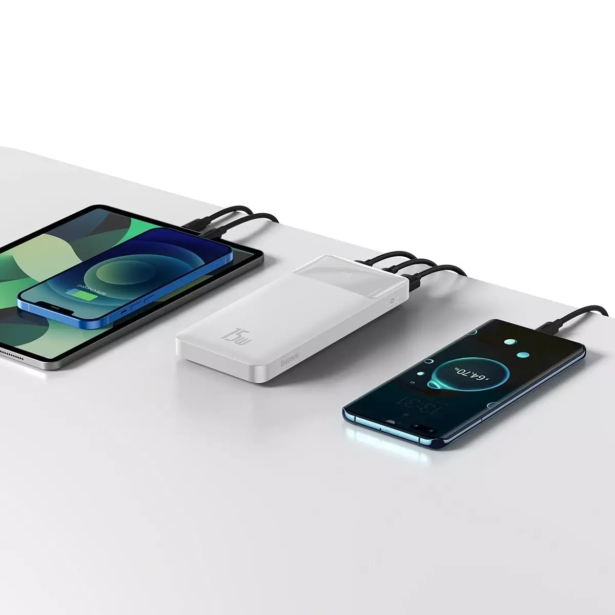 Beyaz powerbank üç cihazı şarj ediyor: tablet, telefon ve başka bir telefon. Beyaz yüzey.