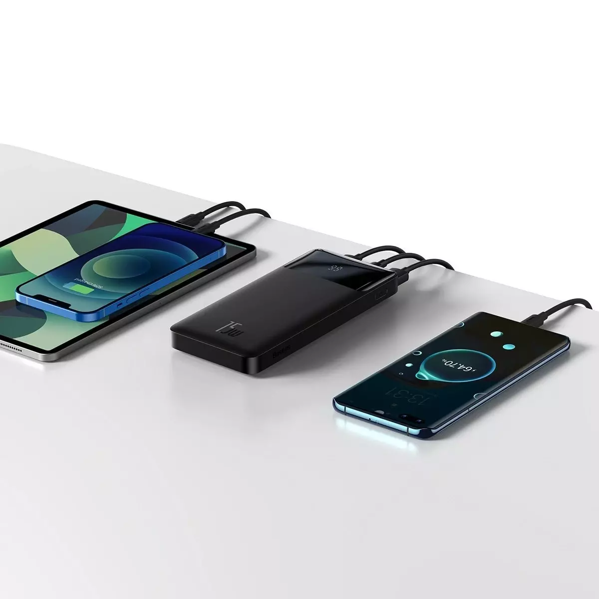 Şarj olan üç cihaz. İki telefon ve bir tablet. Siyah şarj cihazları kullanılıyor.