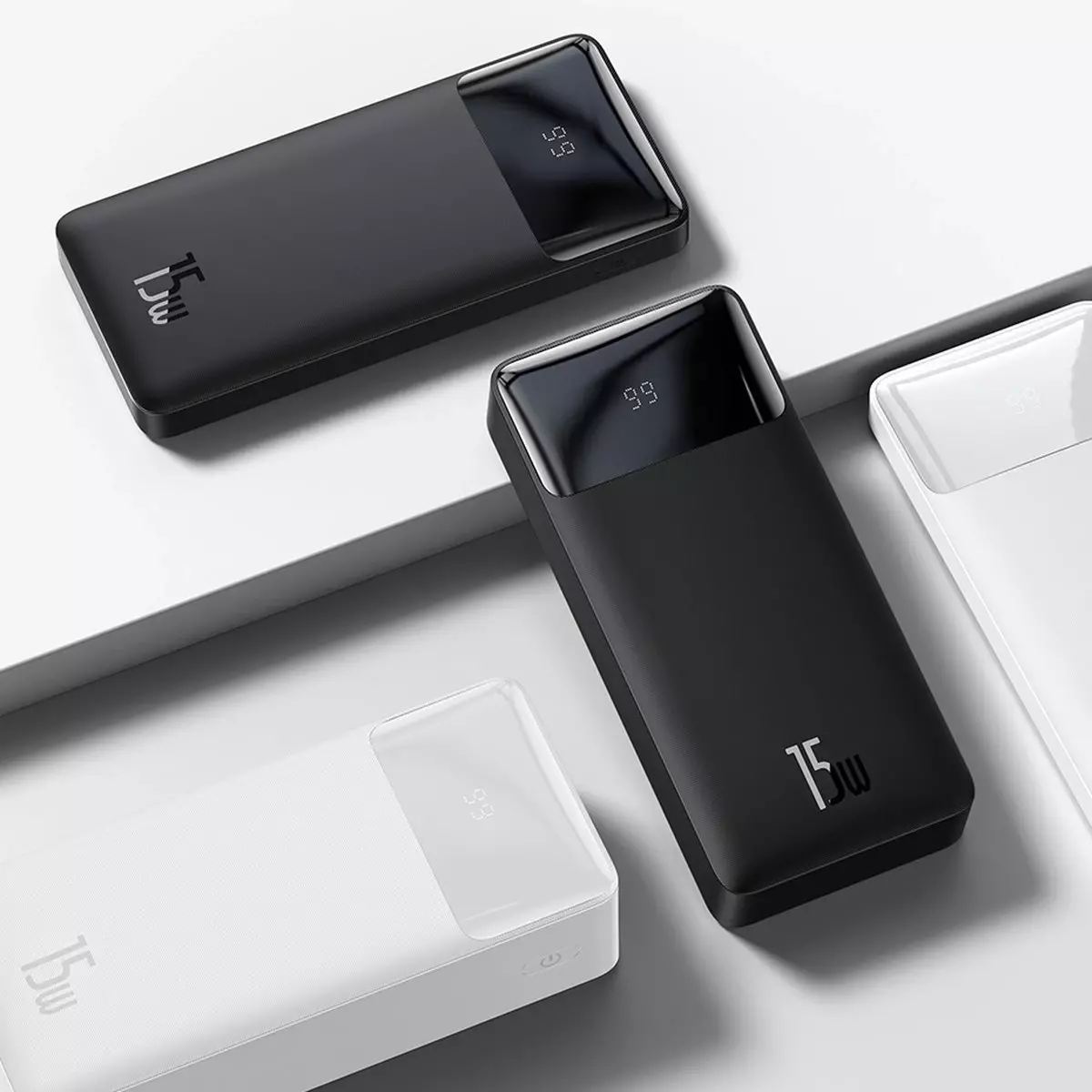 Dijital ekranlı, beyaz yüzey üzerinde üç siyah beyaz powerbank.