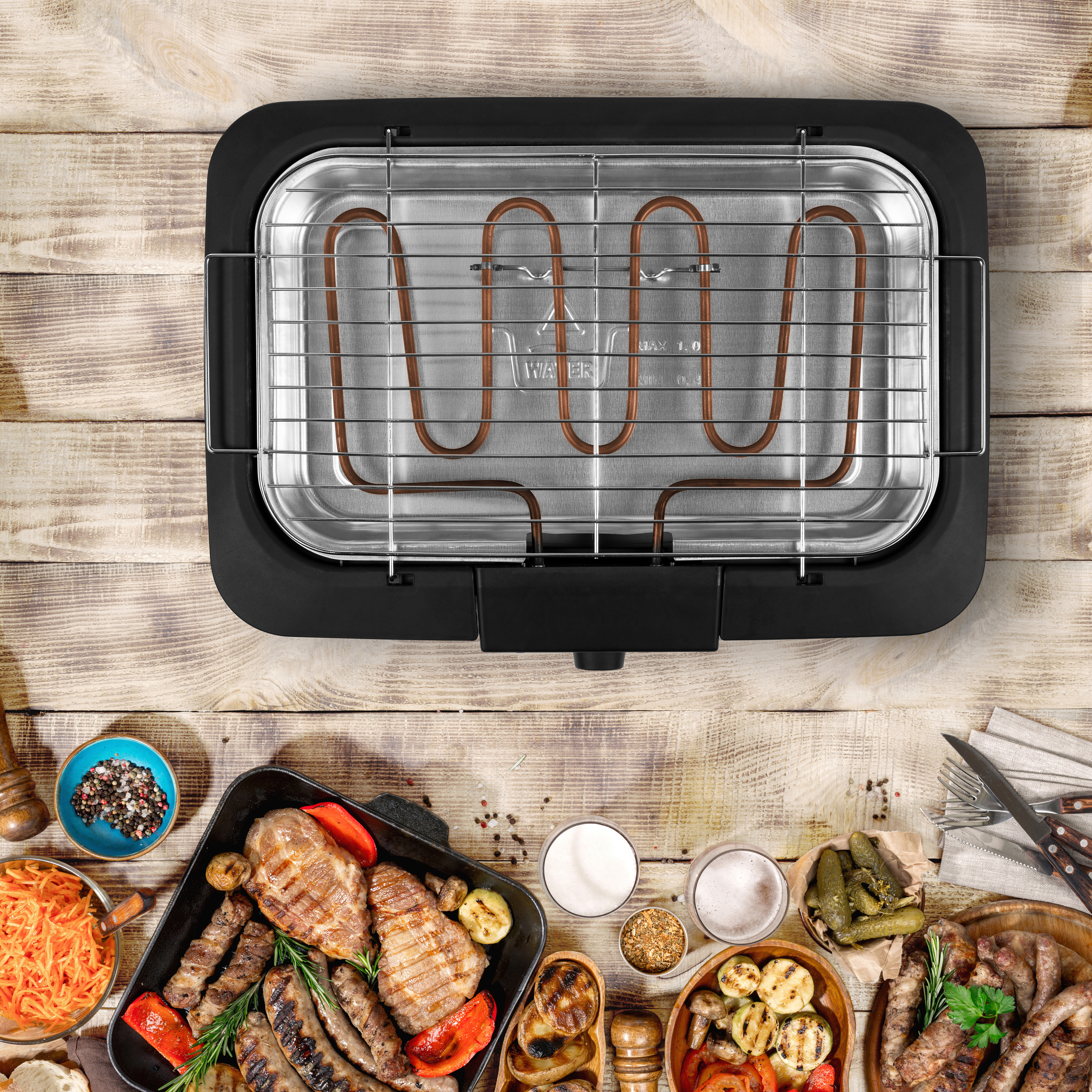Parrilla eléctrica con comida. Carnes, verduras y condimentos a la parrilla están presentes.