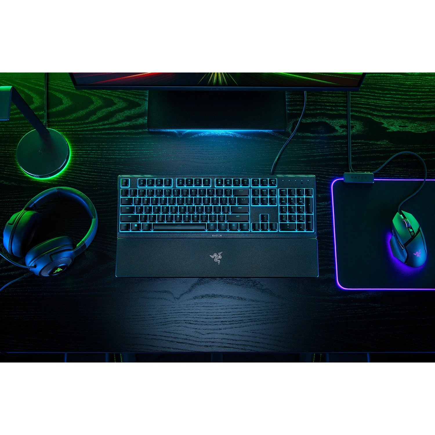Gaming setup on a black desk. Keyboard, mouse, headphones, and monitor are visible.