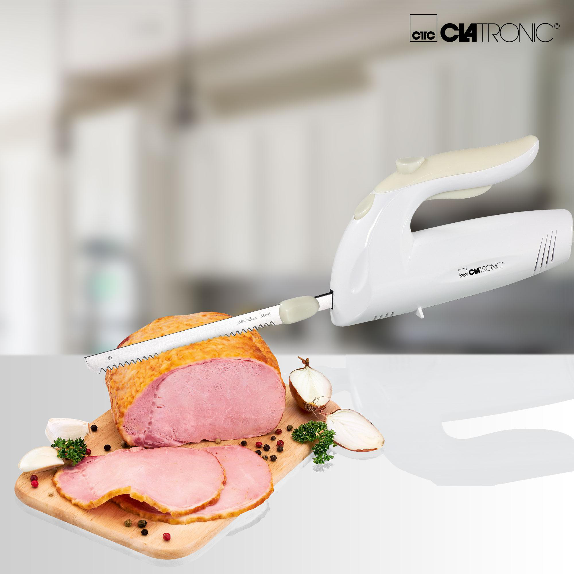 Elektrisches Messer schneidet einen Braten auf einem Holzbrett mit Zwiebel und Petersilie.