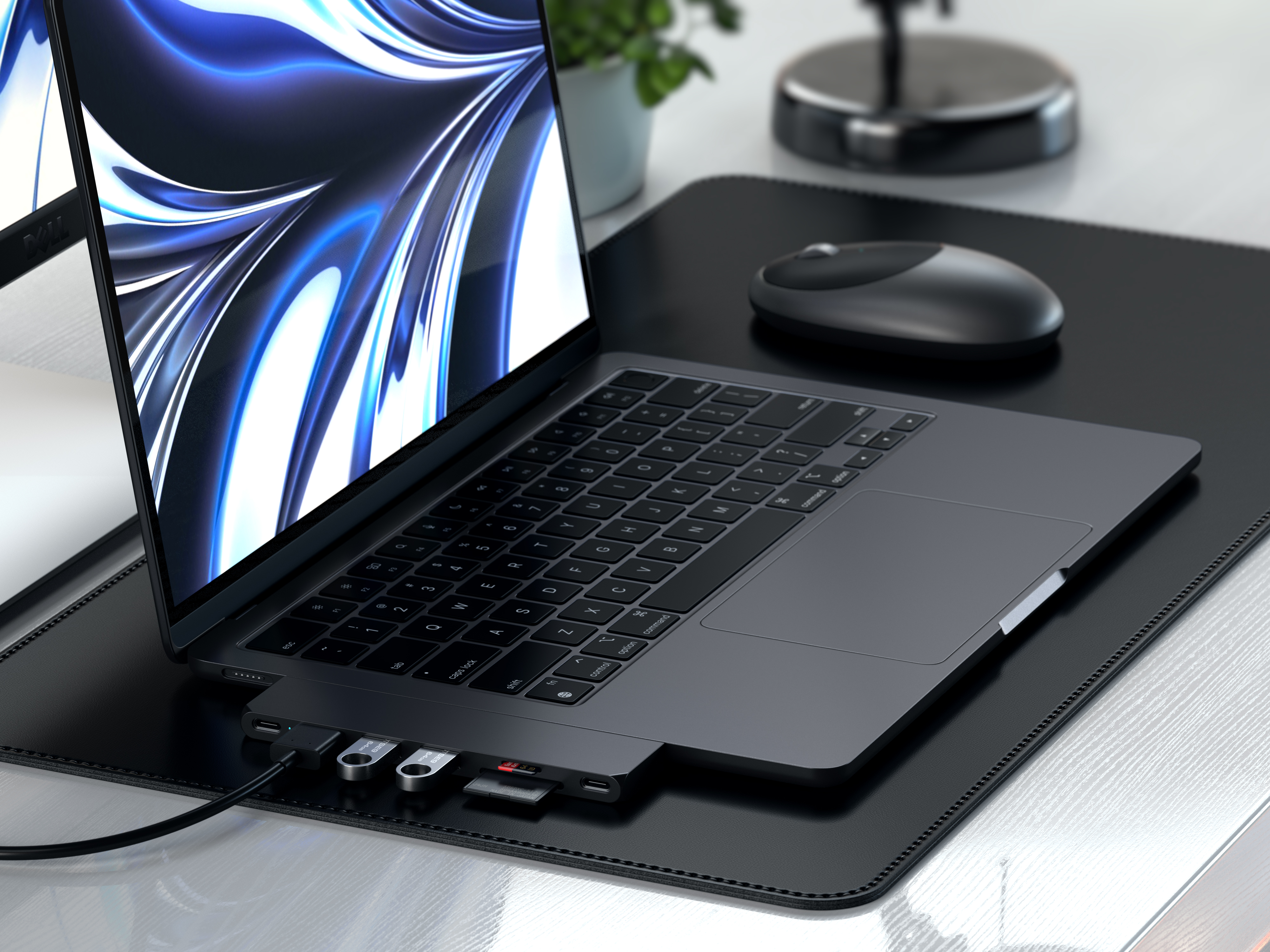 Geöffneter Laptop mit USB-Hub. Schwarzer Schreibtisch, Maus und Monitor sichtbar.