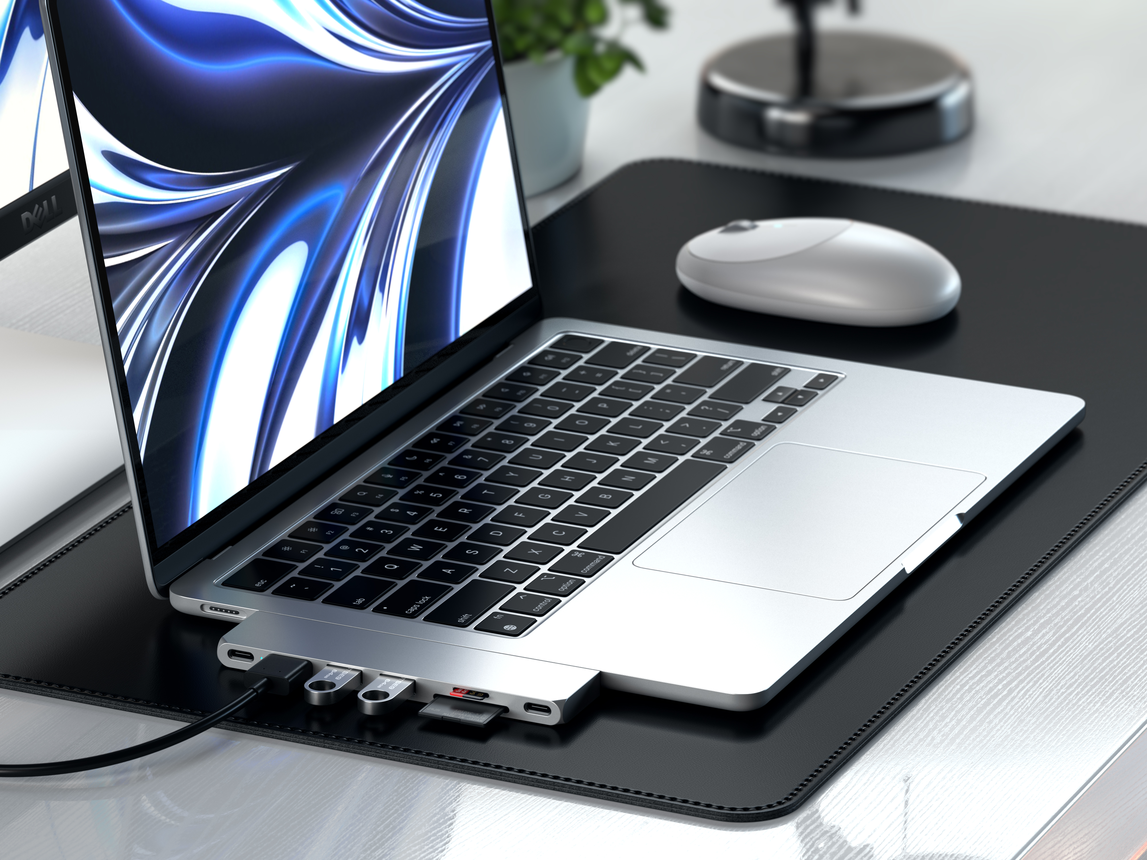 Laptop, an Hub angeschlossen, USB-Laufwerke und Maus auf schwarzer Schreibtischunterlage.