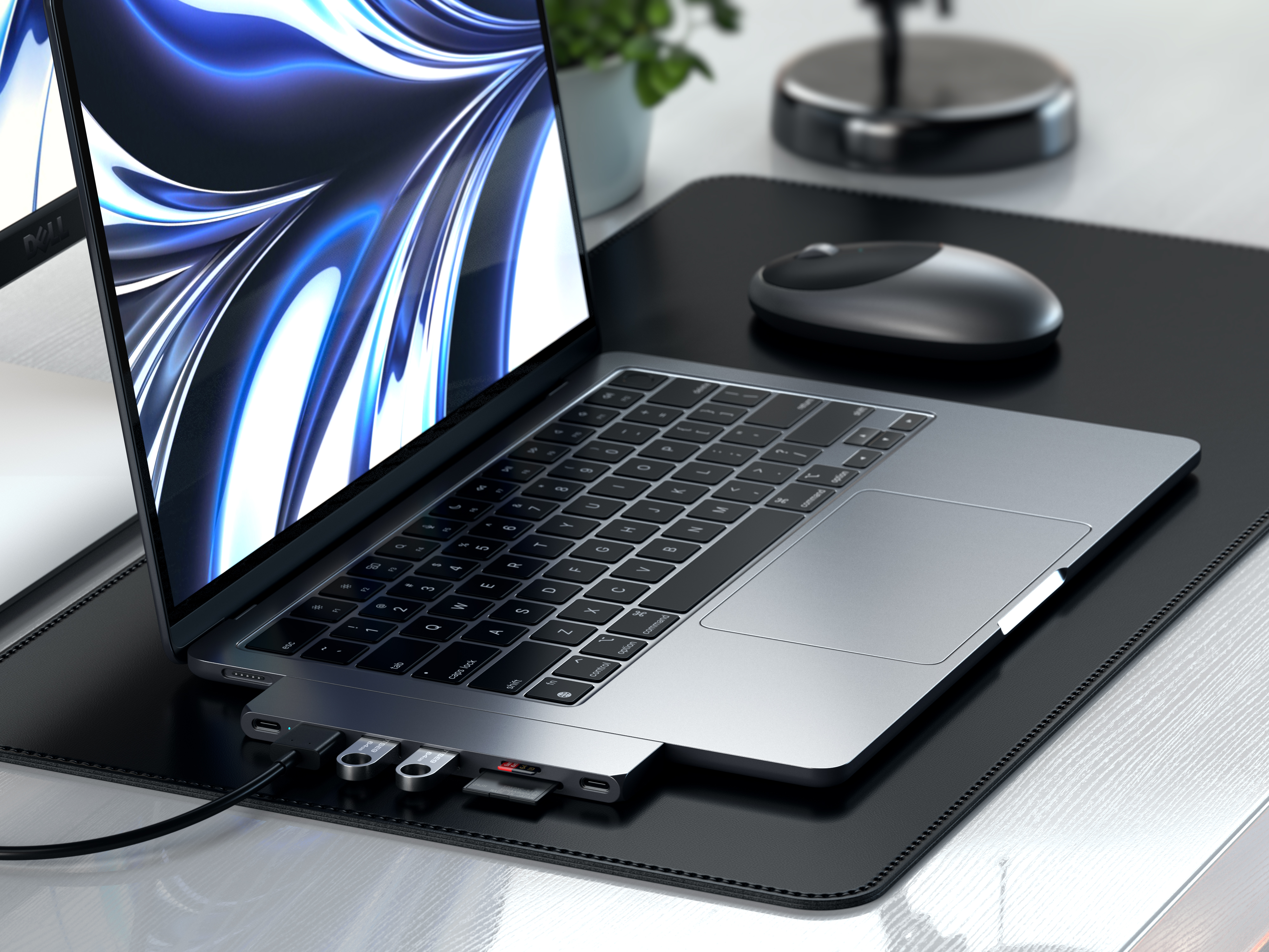 Laptop mit USB-Hub auf schwarzem Schreibtischpad. Maus auf dem Pad. Holzschreibtisch im Hintergrund.