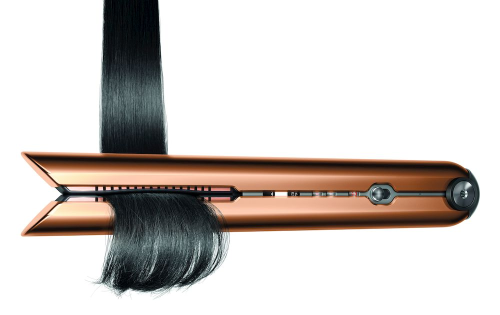 Plancha de pelo de cobre con secciones de cabello negro siendo alisadas.