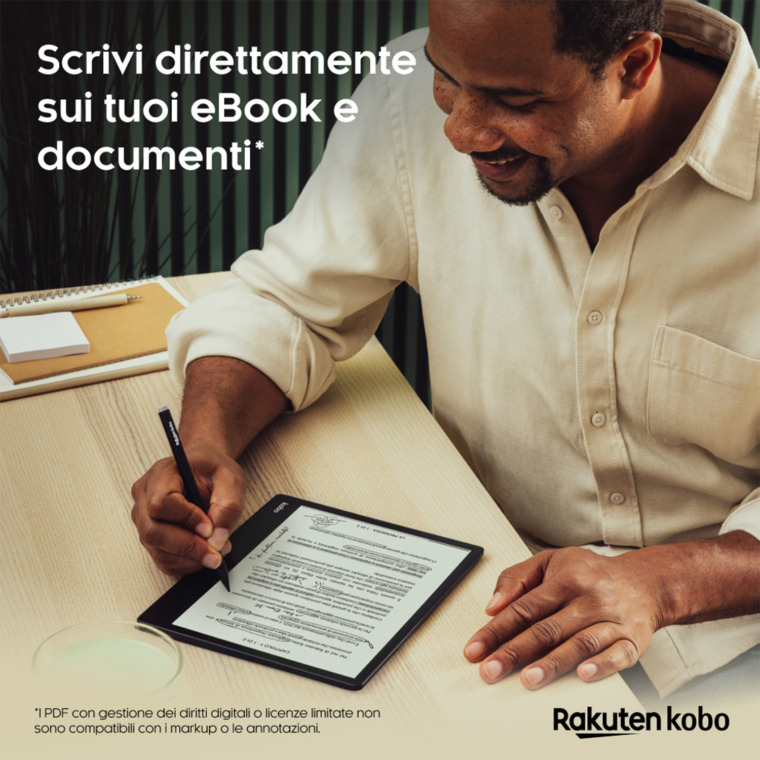 Uomo che scrive su tablet con penna, sorridente, tavolo in legno chiaro.