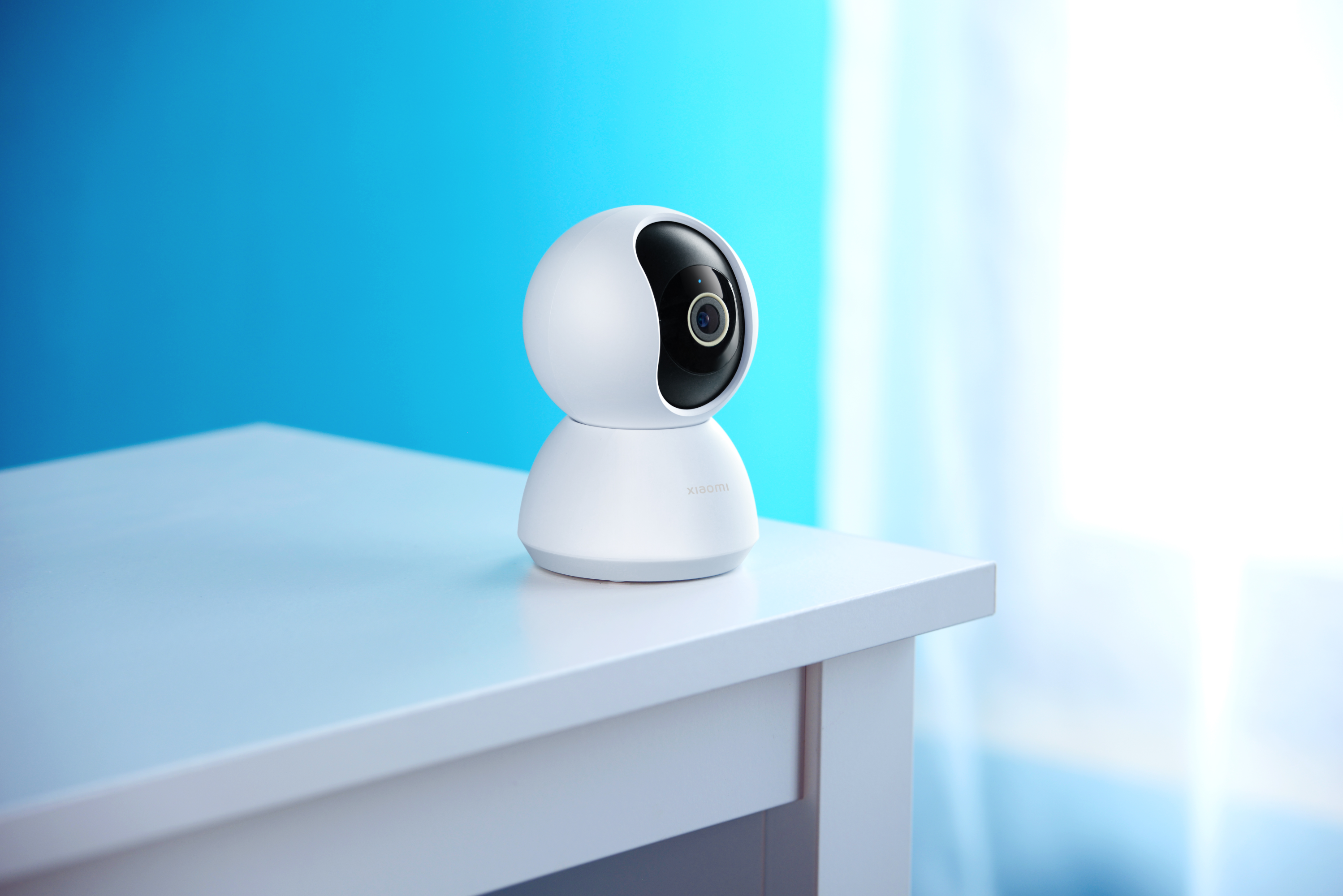 Telecamera di sicurezza bianca su un tavolo bianco. Sfondo blu, focalizzato sulla telecamera.