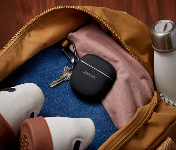 Custodia nera per auricolari Bose, chiave e accessori in una borsa marrone.