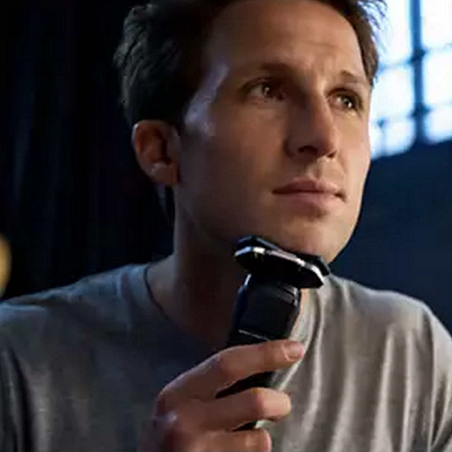 Man shaving with an electric shaver, close up.