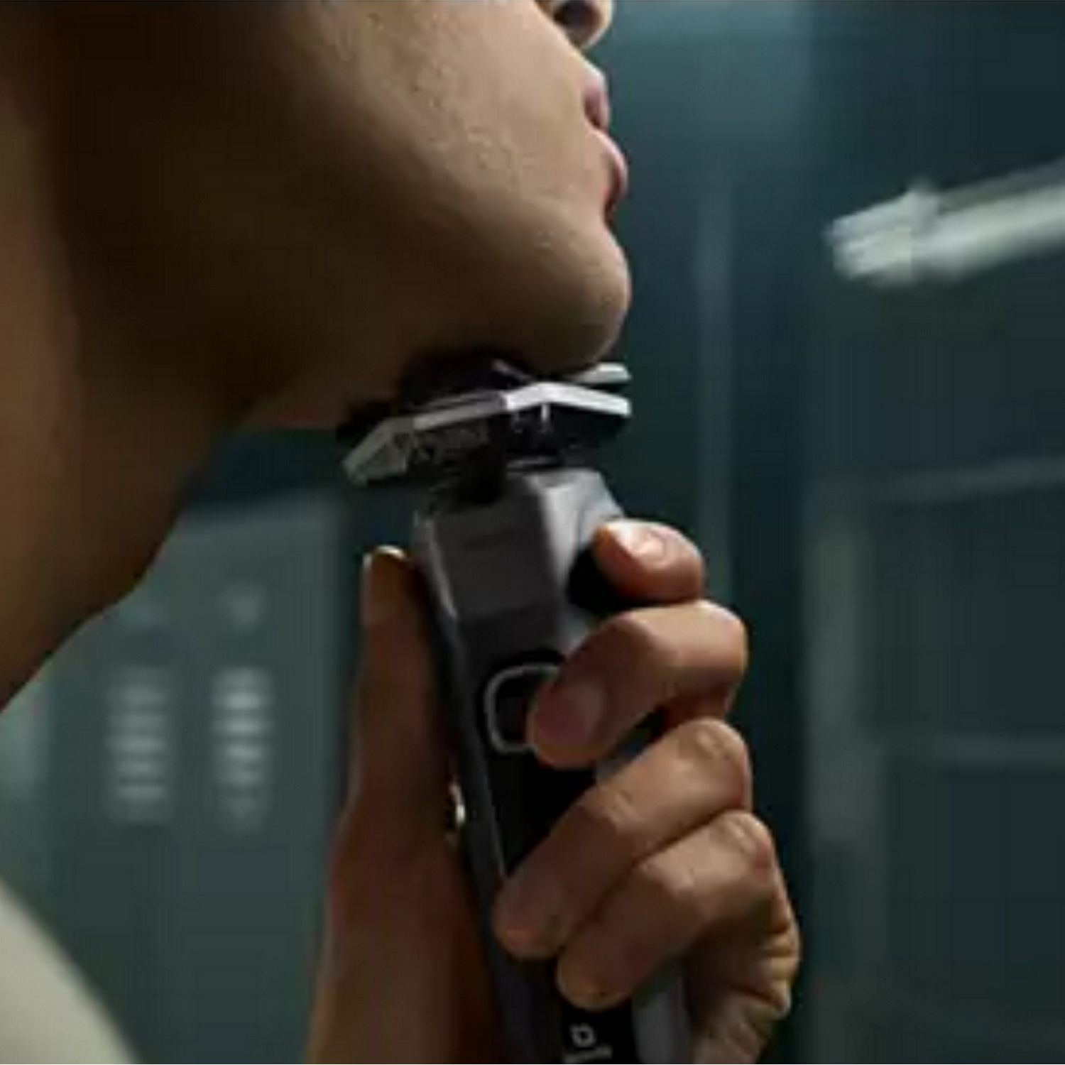 A man shaving with an electric shaver in front of a mirror.