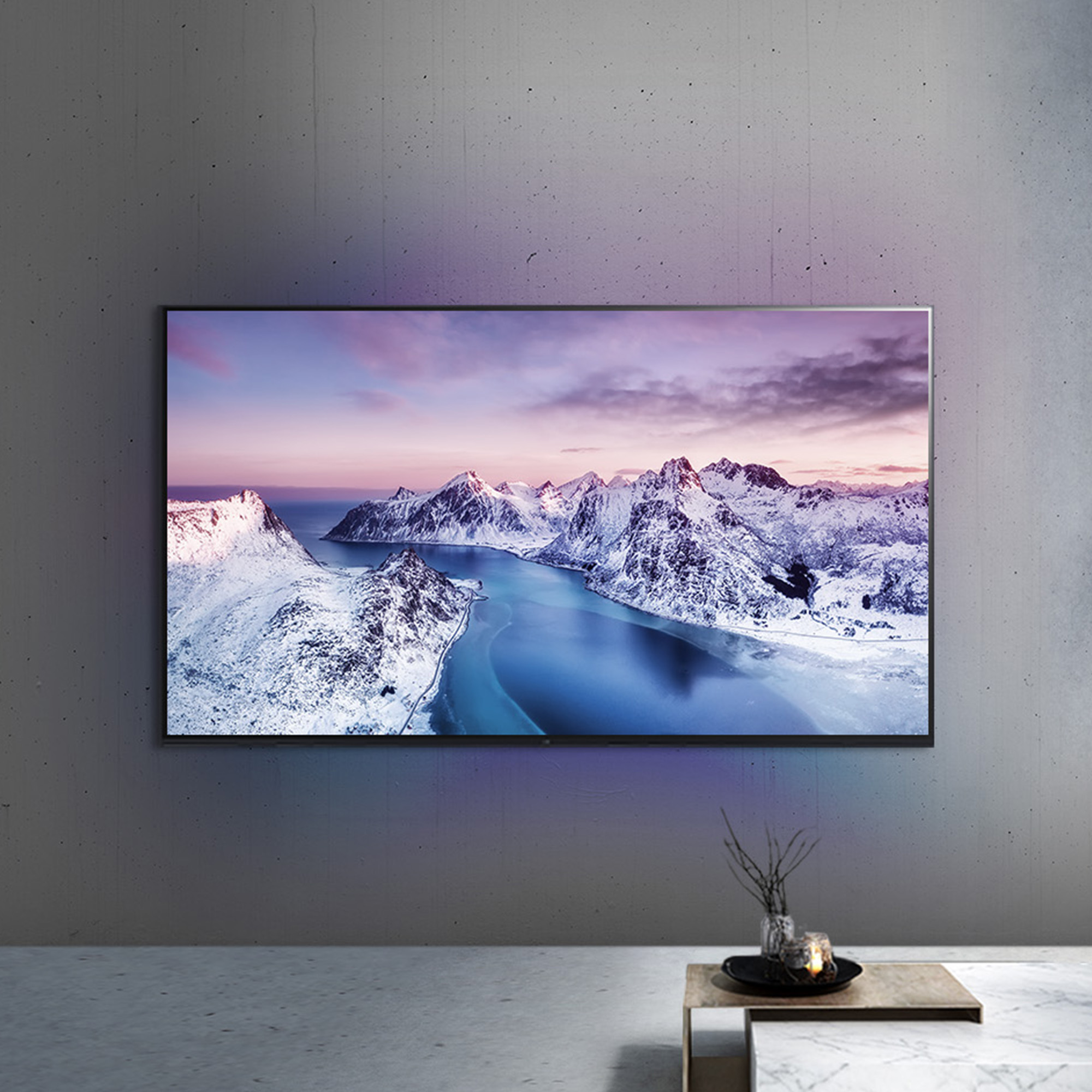 Una pantalla de TV que muestra un paisaje de montaña nevada, montada en una pared.