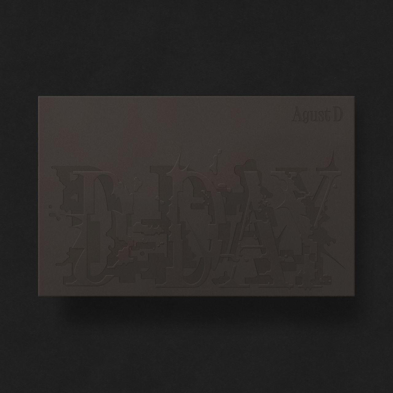 Eine schwarze Box mit geprägtem Text „Agust D“ und „D-DAY“ auf schwarzem Hintergrund.