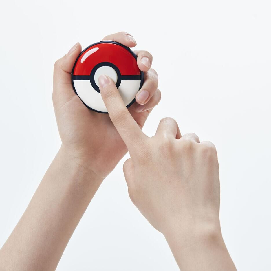 Handen die een rood-witte Poke Ball vasthouden, met een vinger die op de knop drukt.