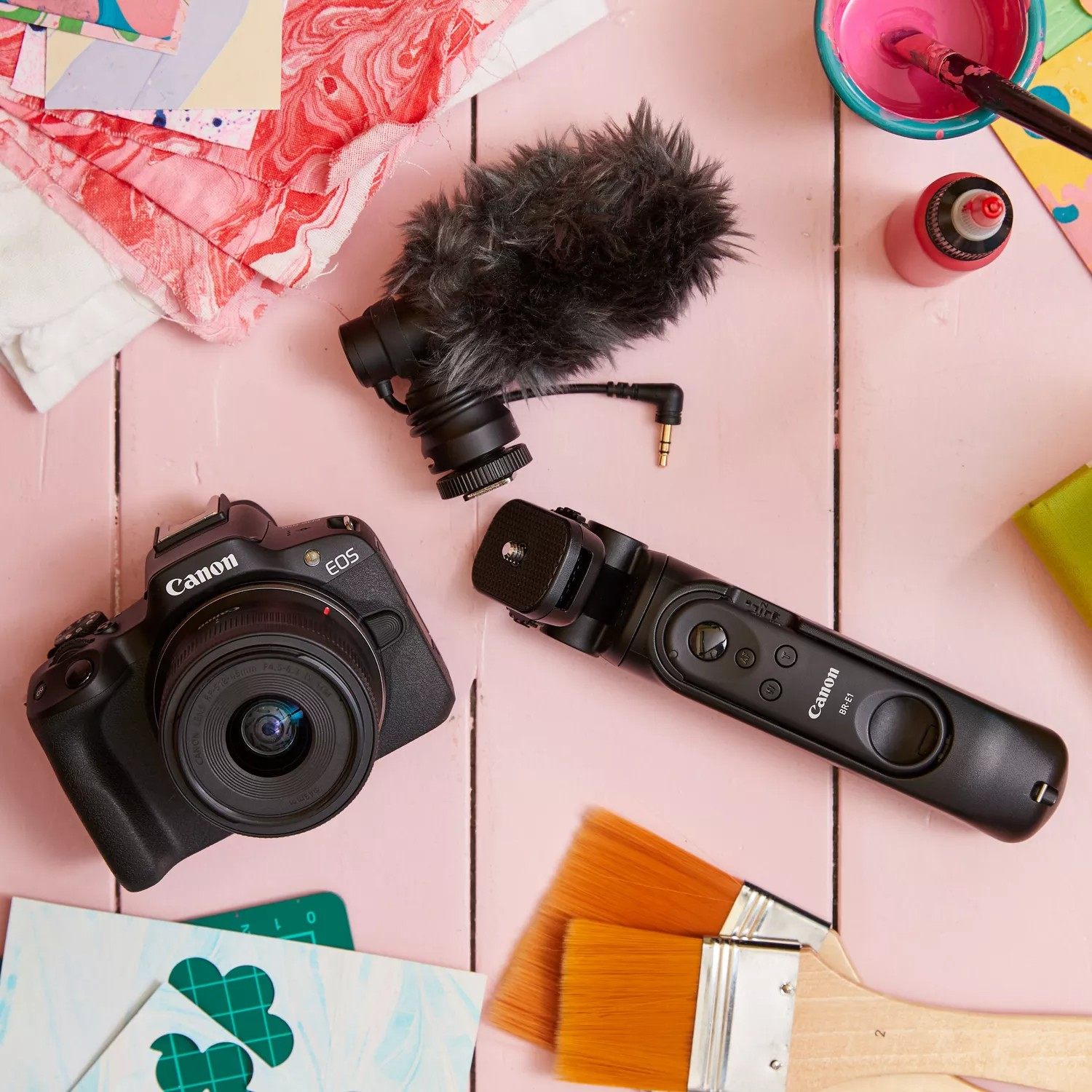 Camera, microfoon en accessoires op een roze oppervlak.