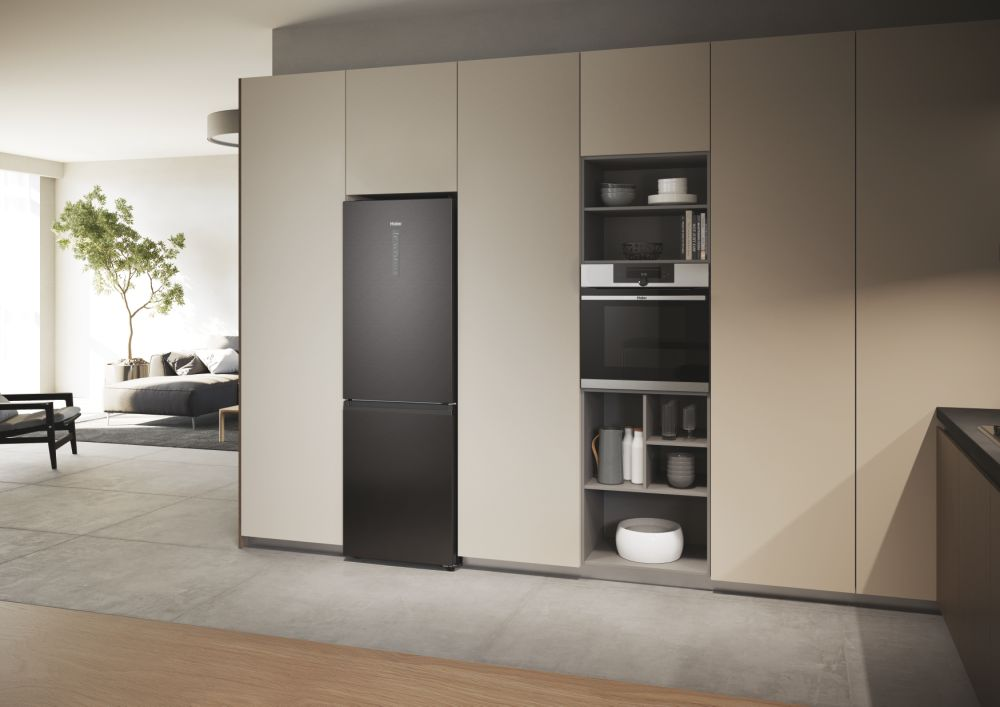 Scena cucina con frigorifero nero, forno a incasso e armadi. Un albero è visibile.