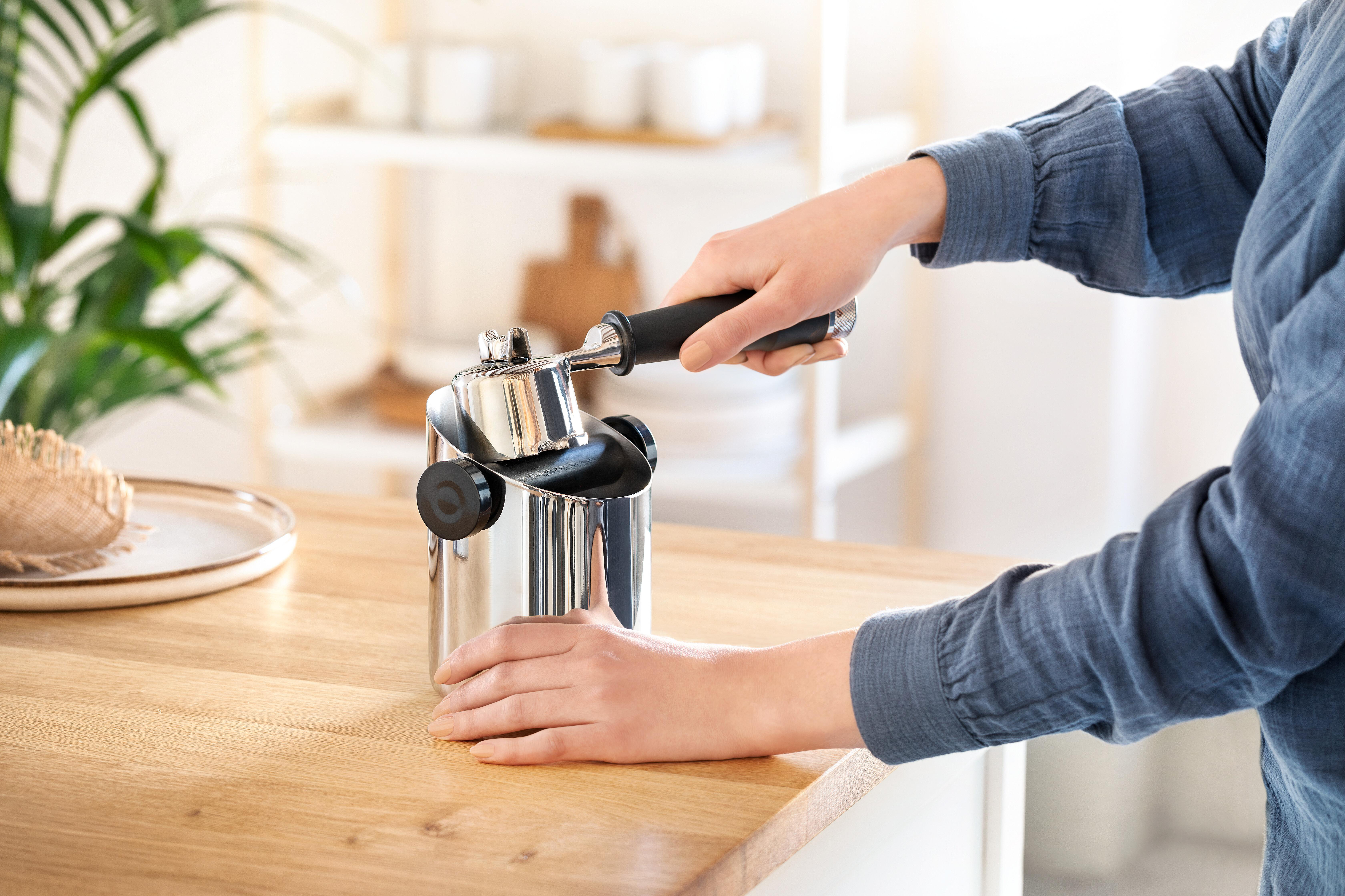 Eine Person, die eine Kaffeemaschine benutzt.
