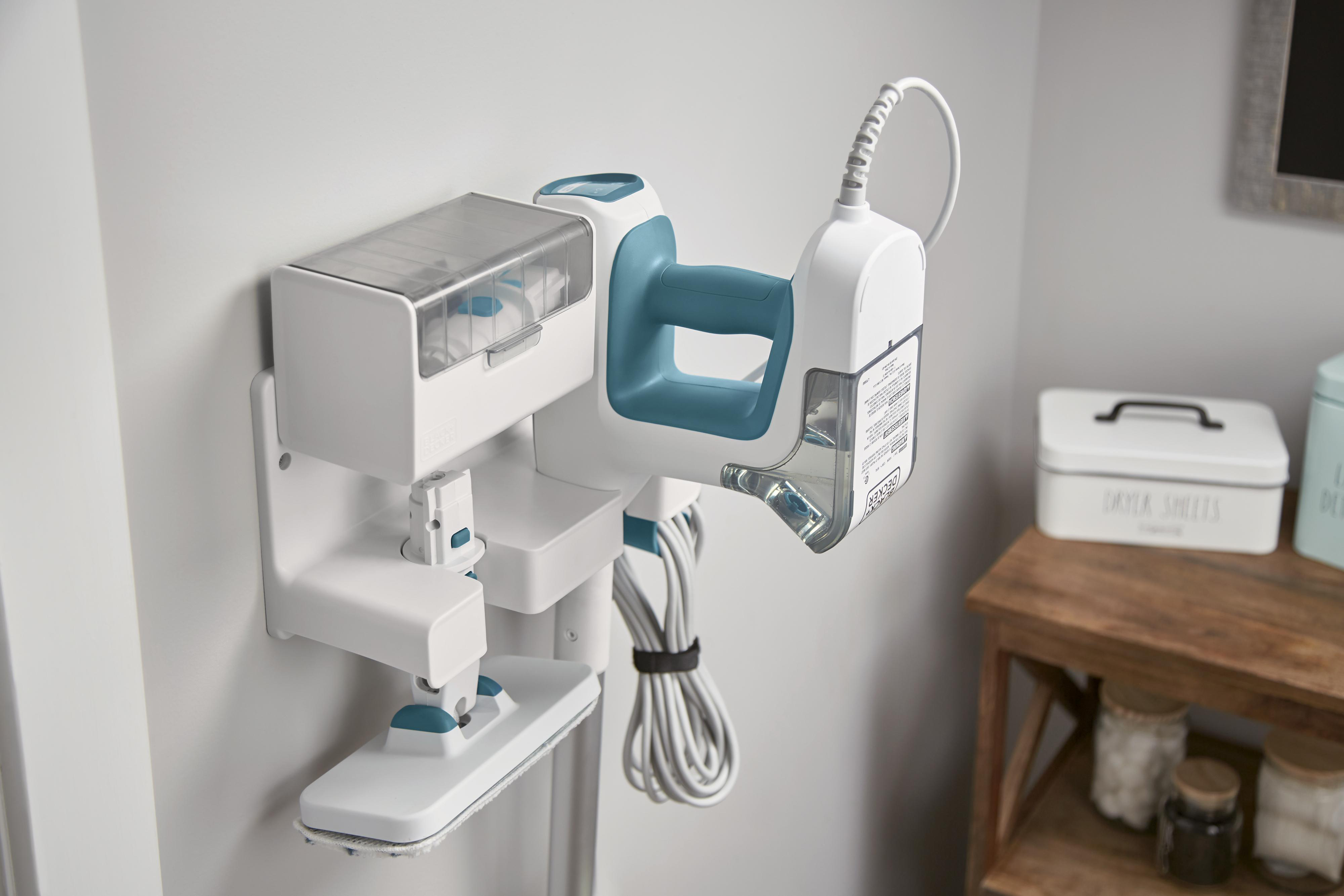 Weiß-blauer Dampfreiniger an der Wand montiert. Zusätzliche Aufsätze und Kabel.