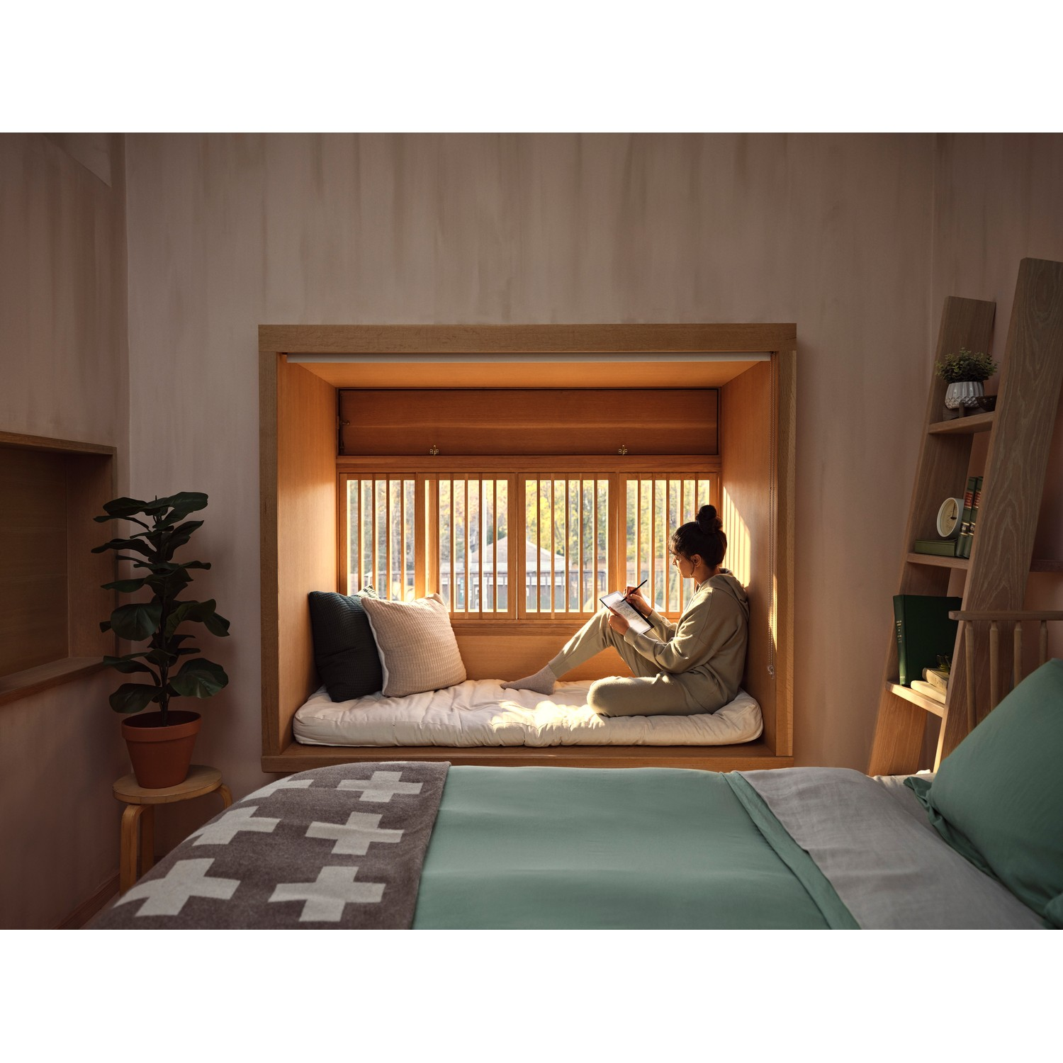 Une femme assise dans un siège près de la fenêtre, lisant un livre, avec un lit et des étagères en arrière-plan.