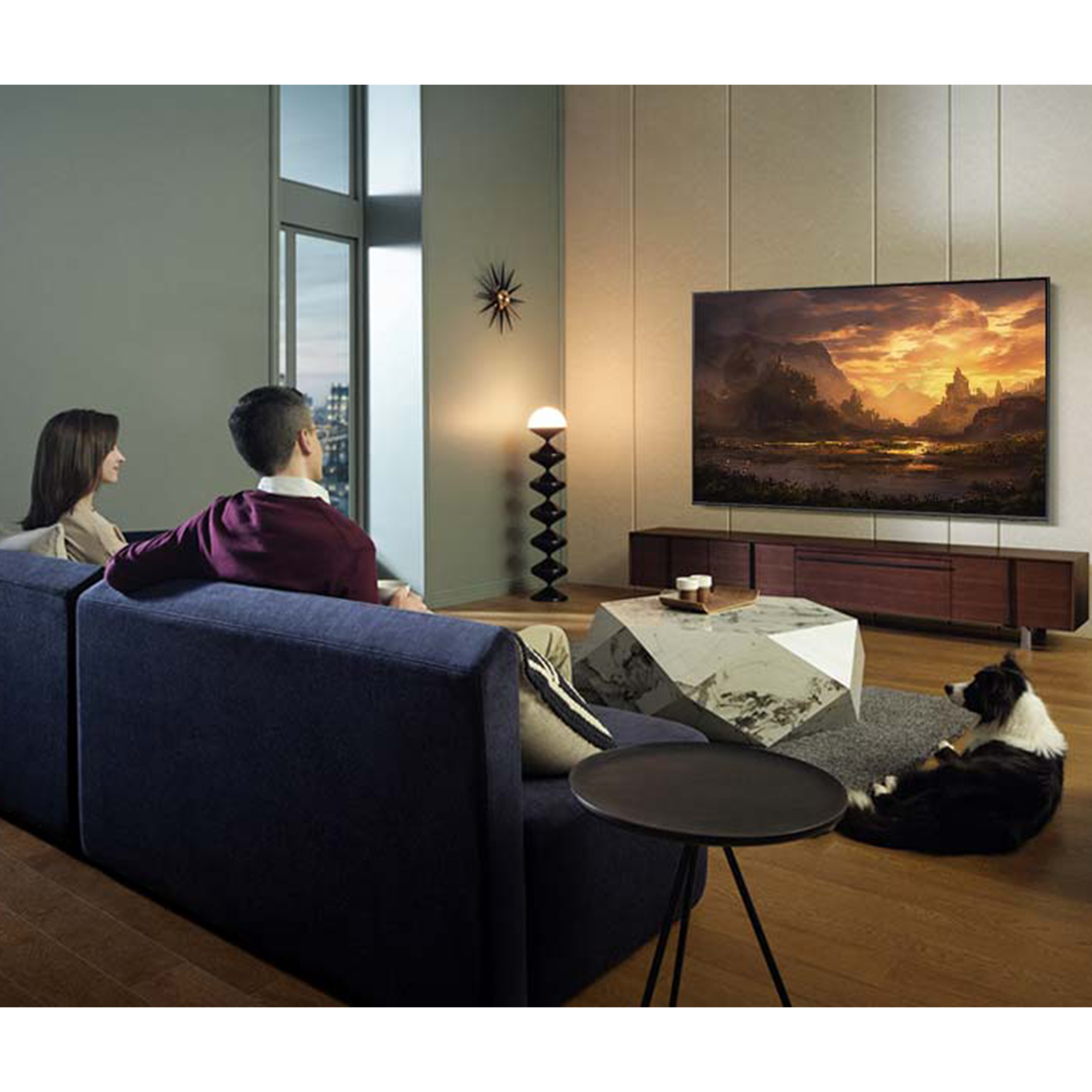 Una pareja ve la televisión. Perro en la alfombra. Salón moderno con una ventana grande.