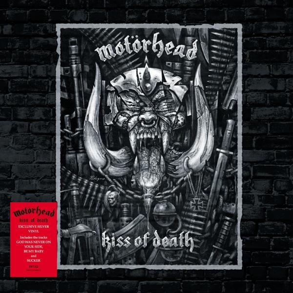 Motörhead album borító, "Kiss of Death". Egy koponya-szerű figura agyarakkal, fegyverekkel körülvéve. Piros szövegdoboz.