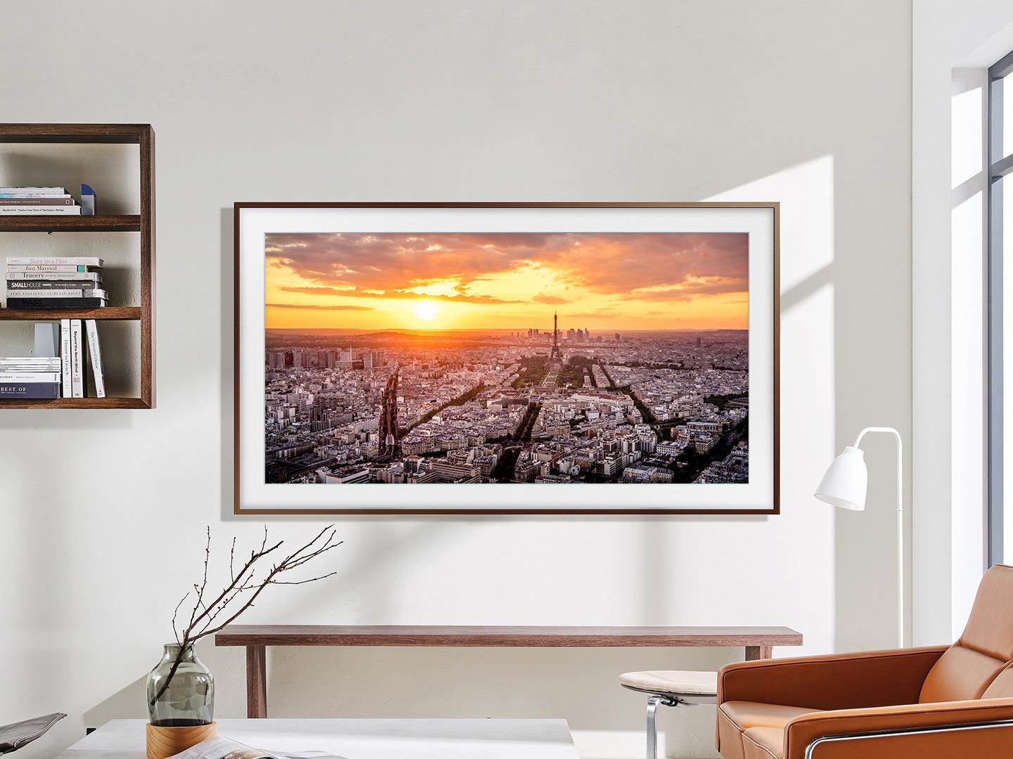 Ein Fernseher zeigt eine Stadtlandschaft mit Sonnenuntergang. Davor stehen ein Tisch und ein Stuhl.