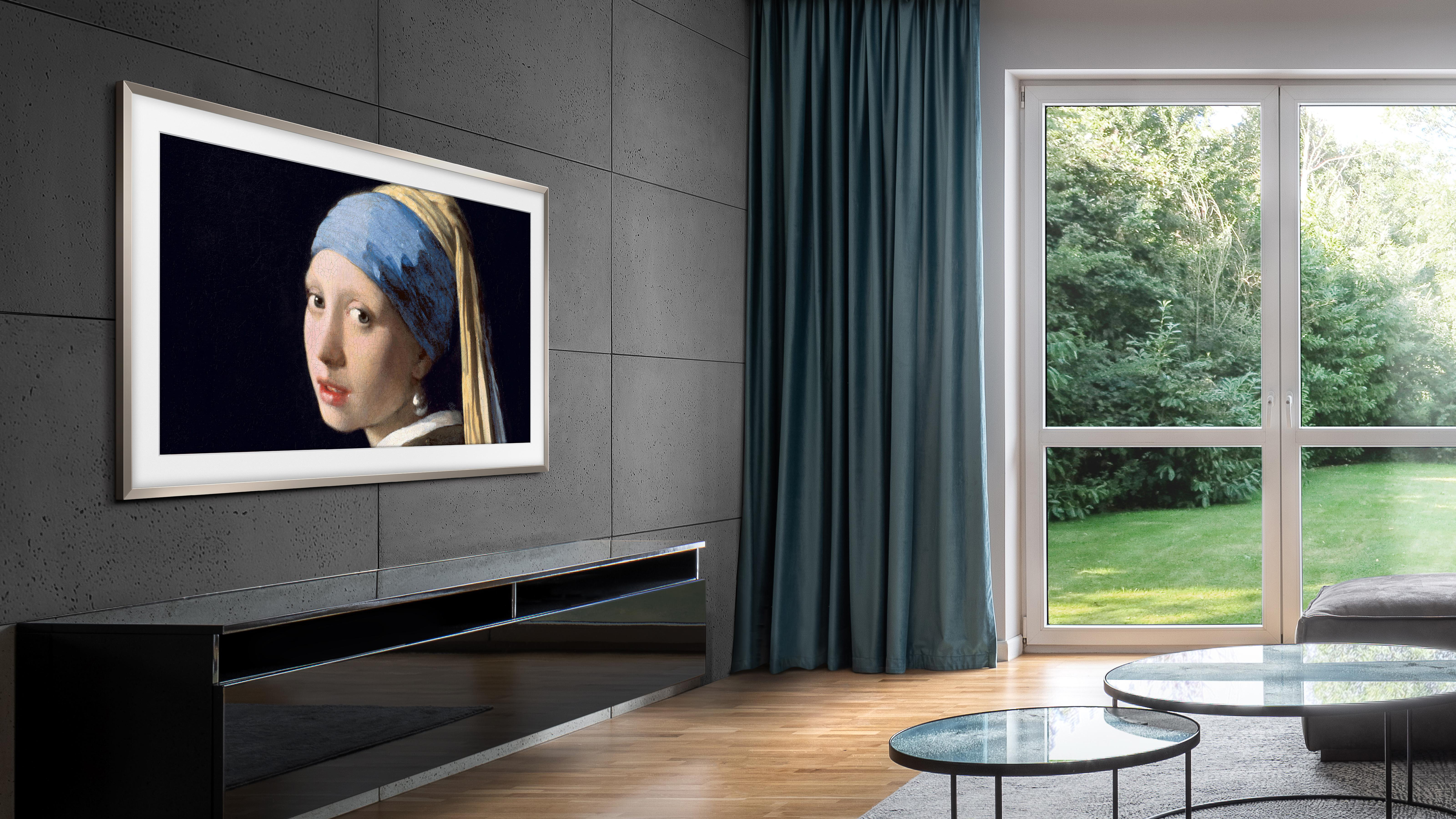 Ein modernes Wohnzimmer mit einem Fernseher, der ein Gemälde an der Wand zeigt. Es gibt ein Fenster.
