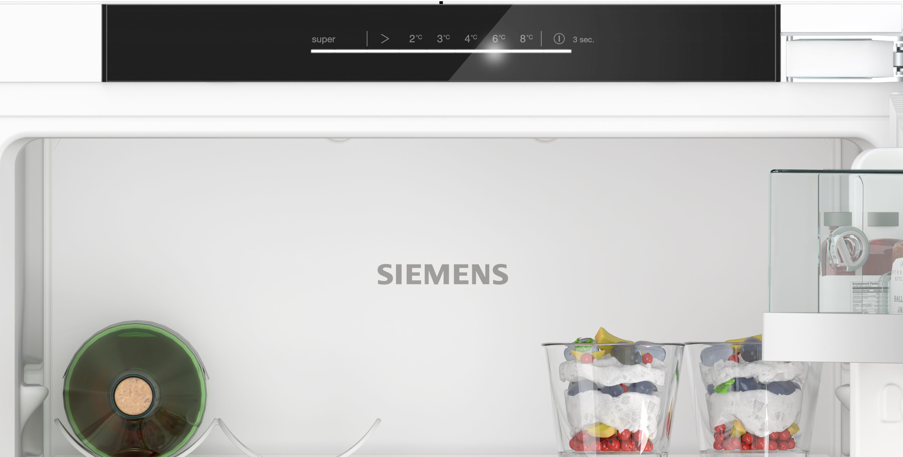 Refrigerator interior. Black control panel. Text: Siemens. Glass cups with fruit. Wine bottle. Shelves with items.