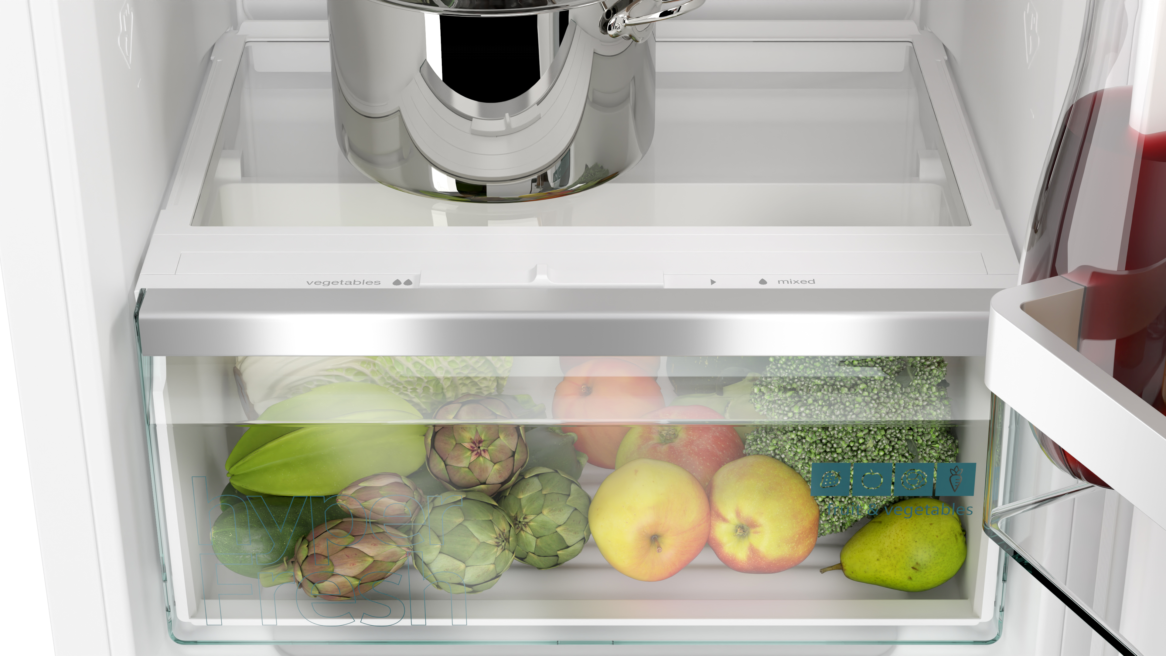 Refrigerator interior. Vegetable drawer with artichokes, apples, and more. A pot sits above.