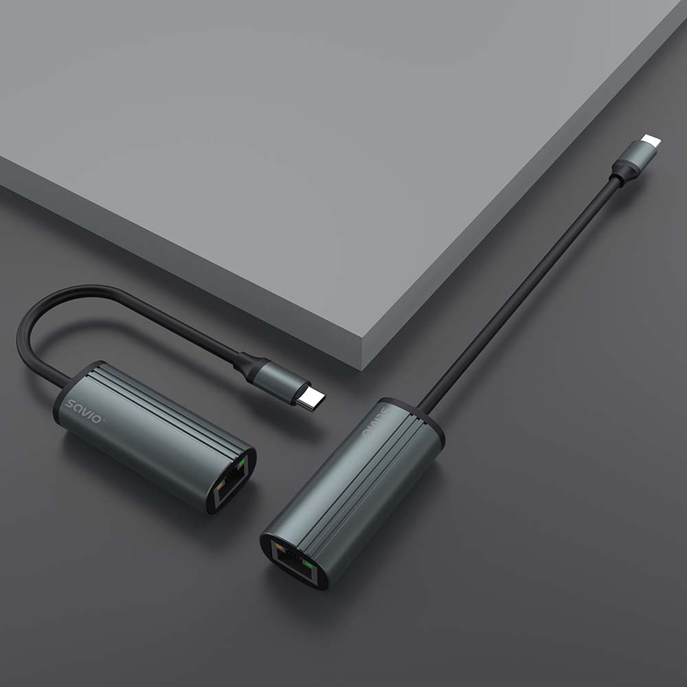 Két szürke Savio USB-C-Ethernet adapter szürke felületen. Az egyik ívelt, a másik egyenes.