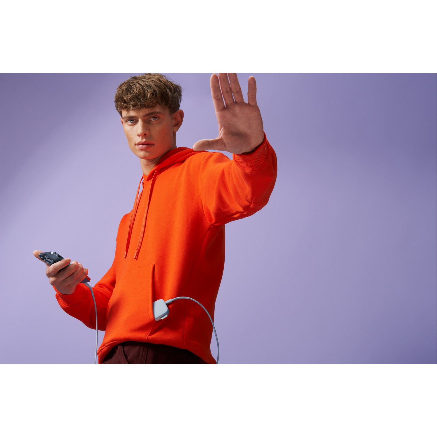 Homme en sweat à capuche orange, téléphone, câble et geste d'arrêt.