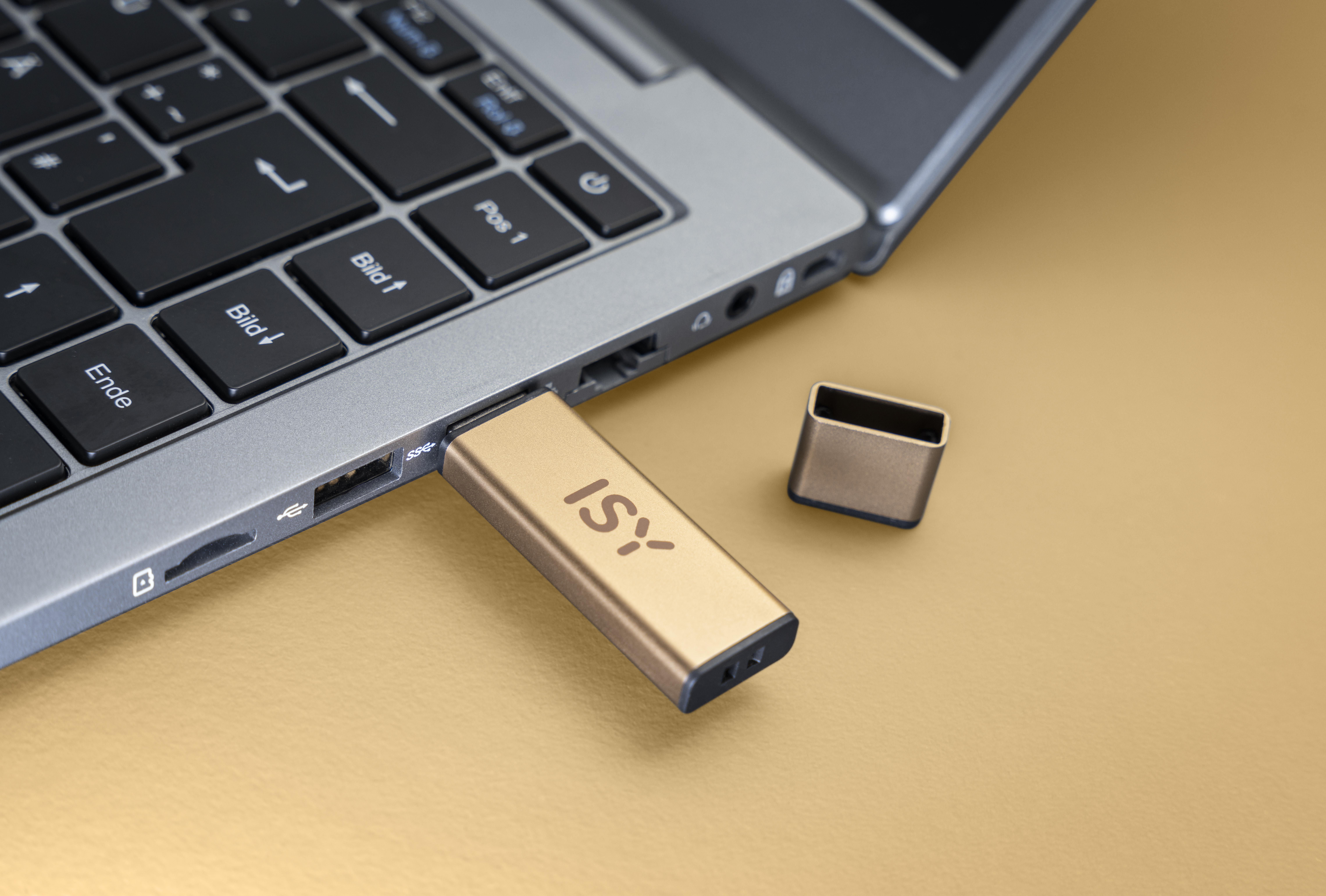 Ein goldfarbener USB-Stick, der in einen Laptop eingesteckt ist, mit der Marke "ISY".