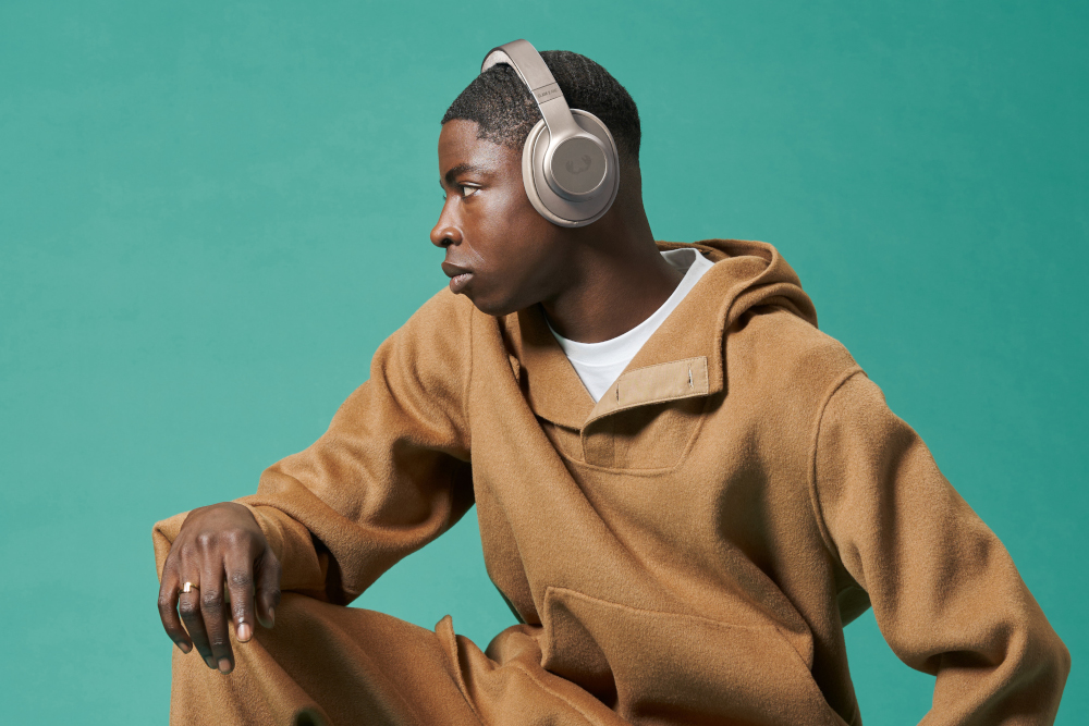 Man met een bruine koptelefoon, bruine hoodie en broek, die wegkijkt.
