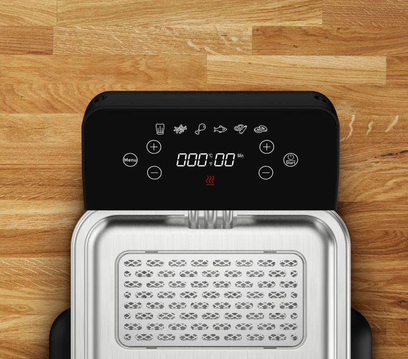 Draufsicht auf eine schwarze Heißluftfritteuse mit Digitalanzeige. Holz Hintergrund.
