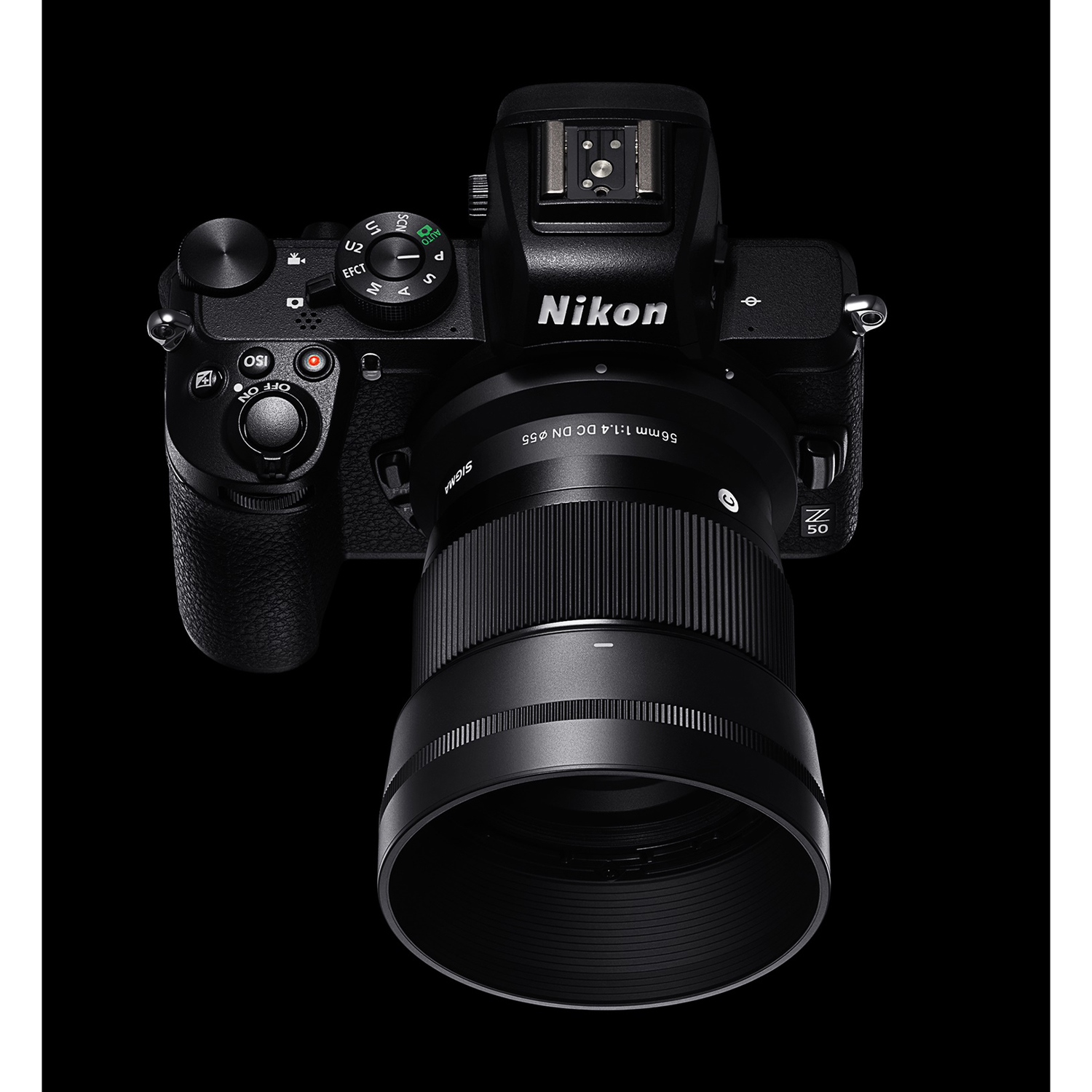 Fotocamera Nikon nera con obiettivo Sigma, vista dall'alto, su sfondo nero.