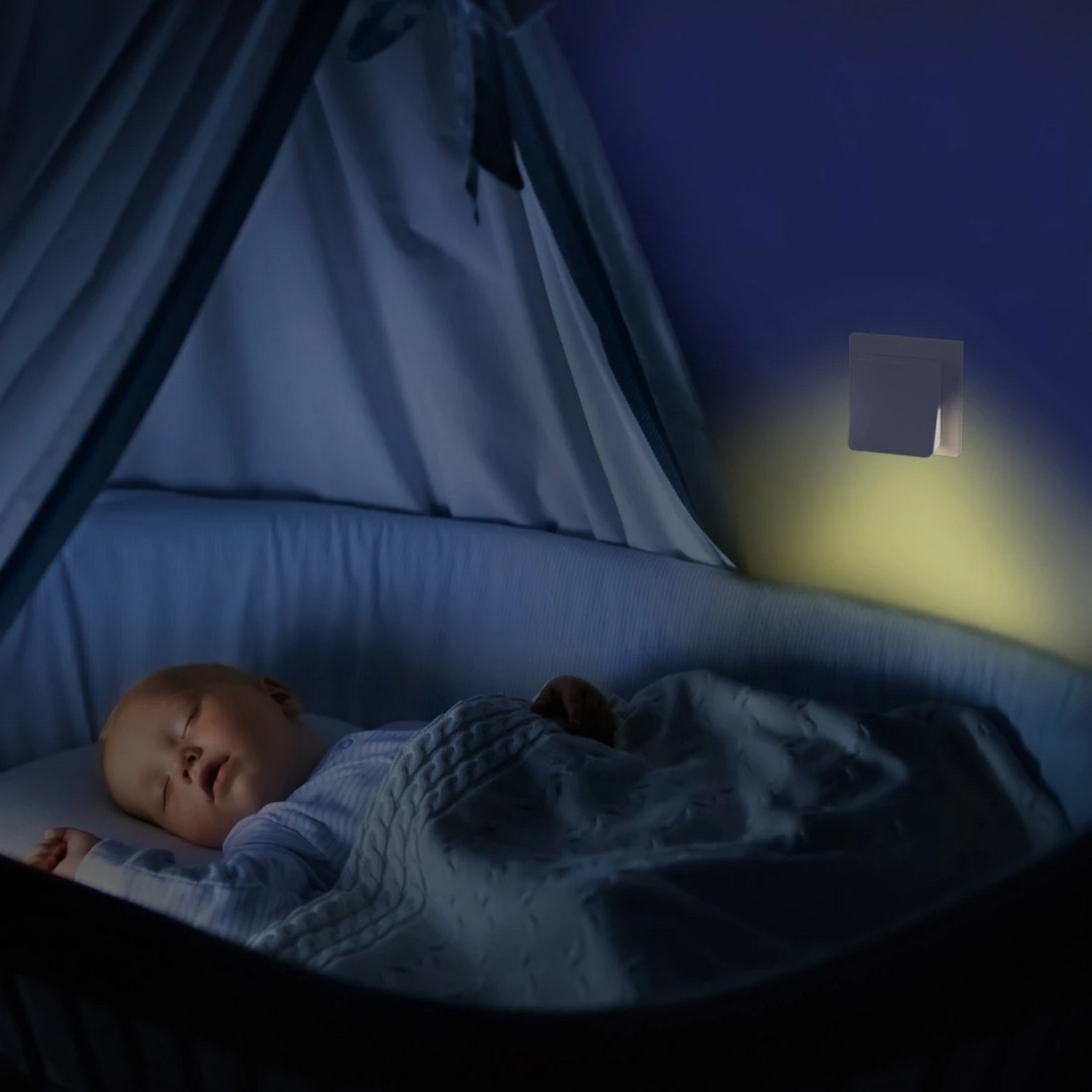 Baby sleeping in a crib with a night light illuminating the wall.