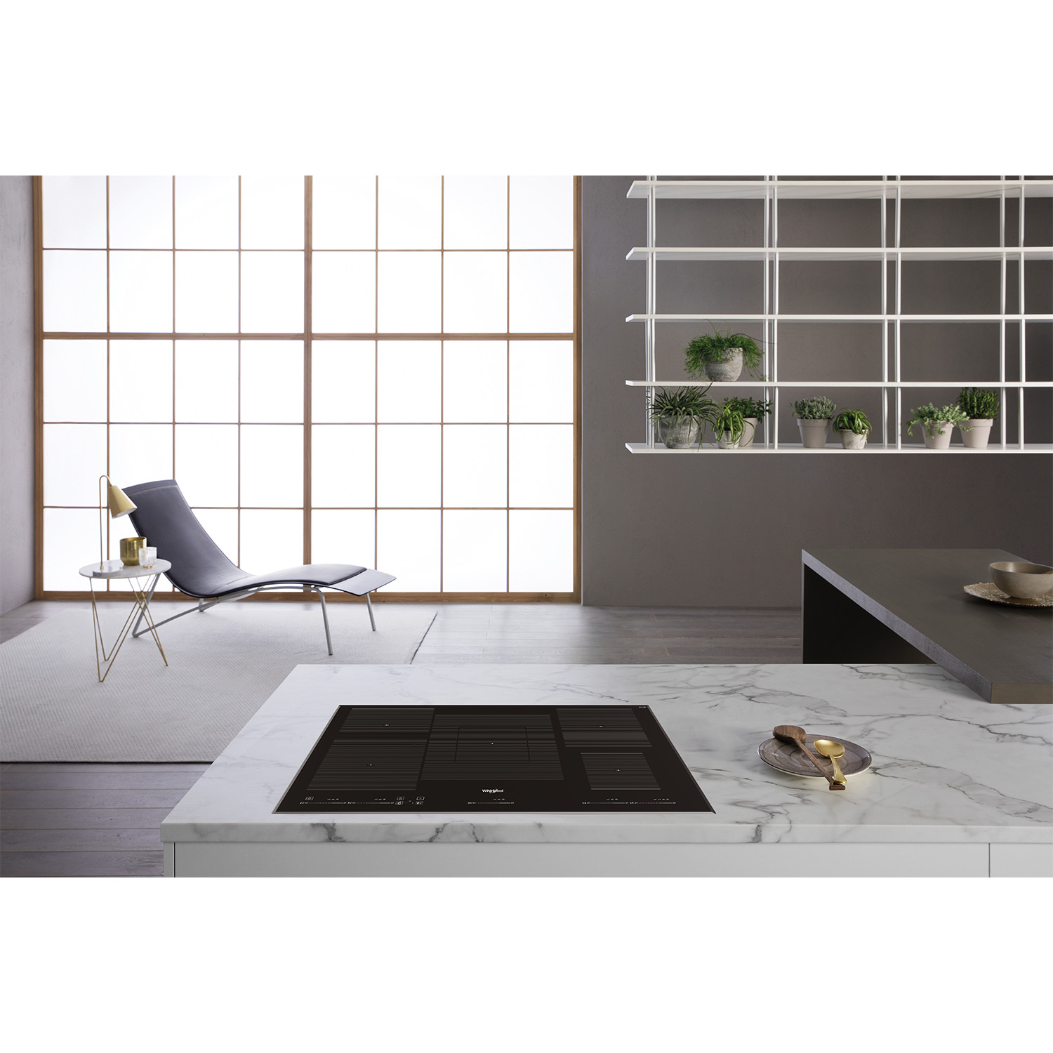 Cucina moderna con piano di lavoro in marmo, piano cottura a induzione e decorazioni.