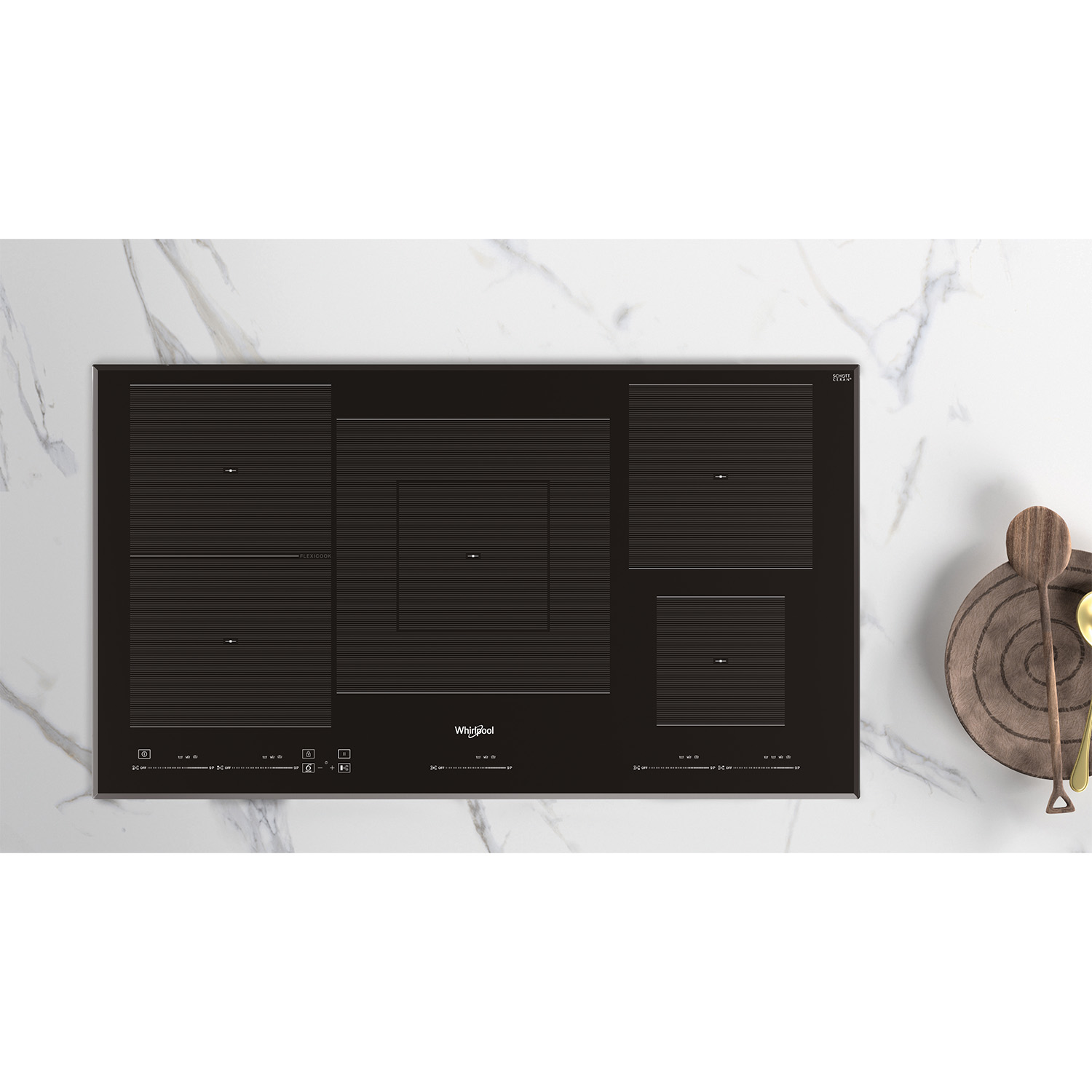 Un piano cottura a induzione nero a quattro fuochi su un piano di lavoro in marmo con cucchiai di legno.