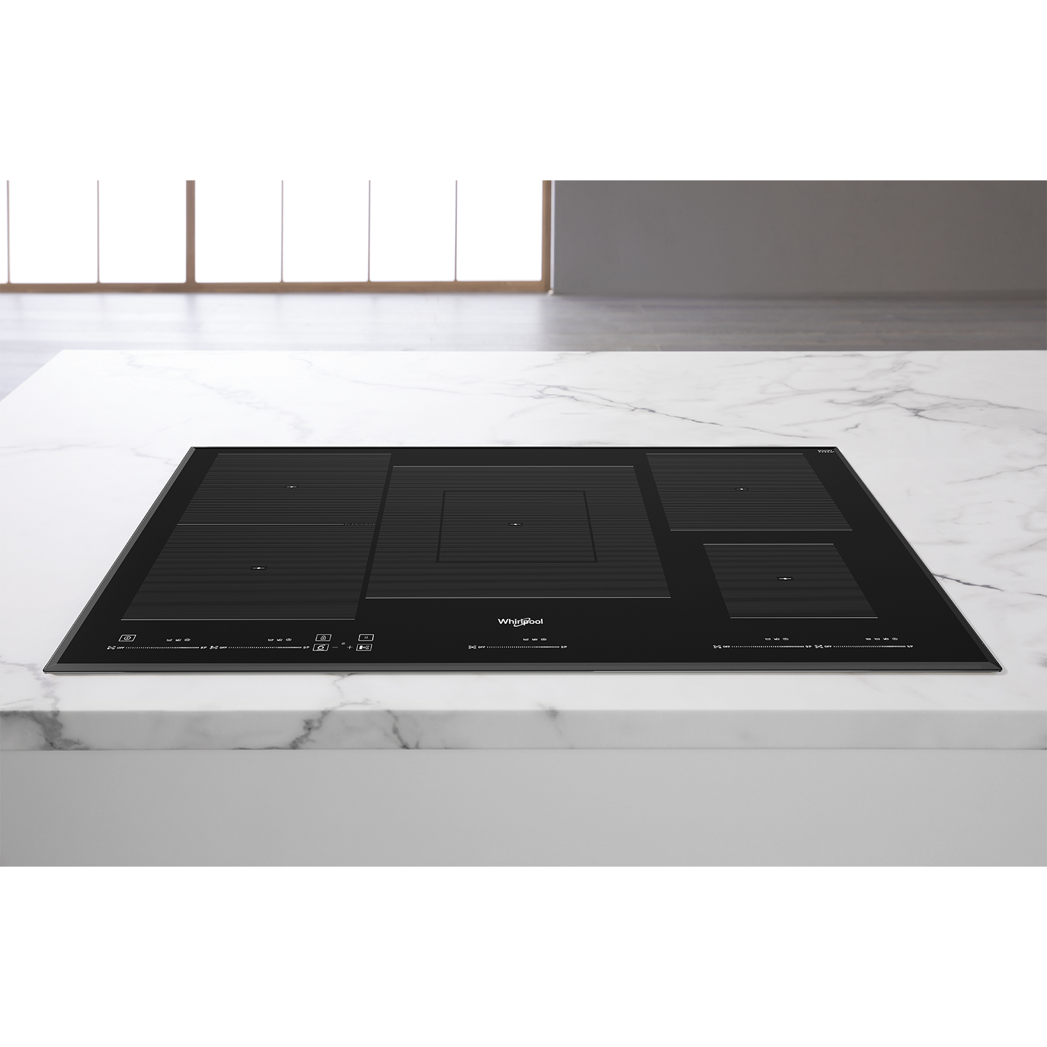 Un piano cottura a induzione nero su un piano di lavoro in marmo bianco, con zone cottura.