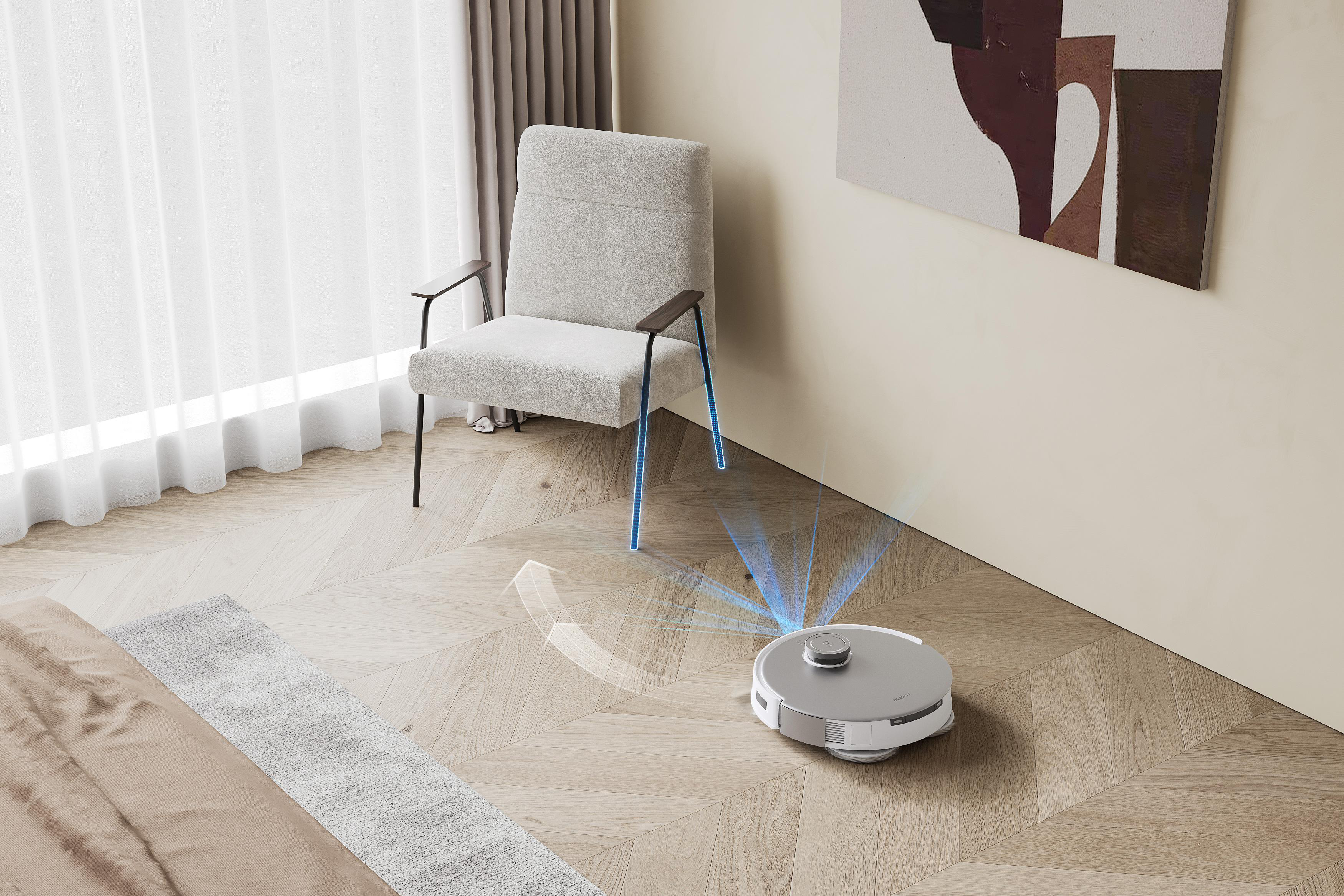 Ein Roboter-Staubsauger reinigt einen Raum. Ein Stuhl und ein Teppich befinden sich ebenfalls im Raum. Blaue Linien zeigen den Weg.