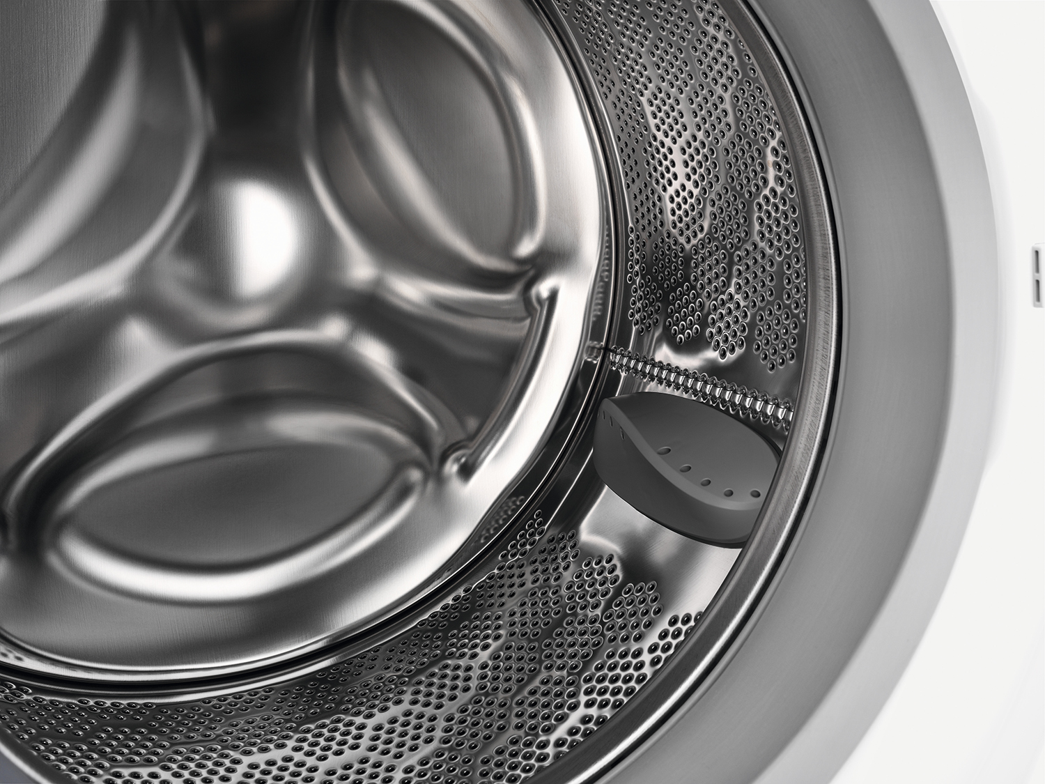 Close-up of a washing machine drum interior, showing the perforated steel and paddle.