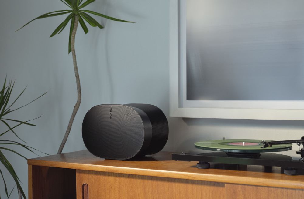 Two black speakers on a wooden cabinet, a record player and a green vinyl record.