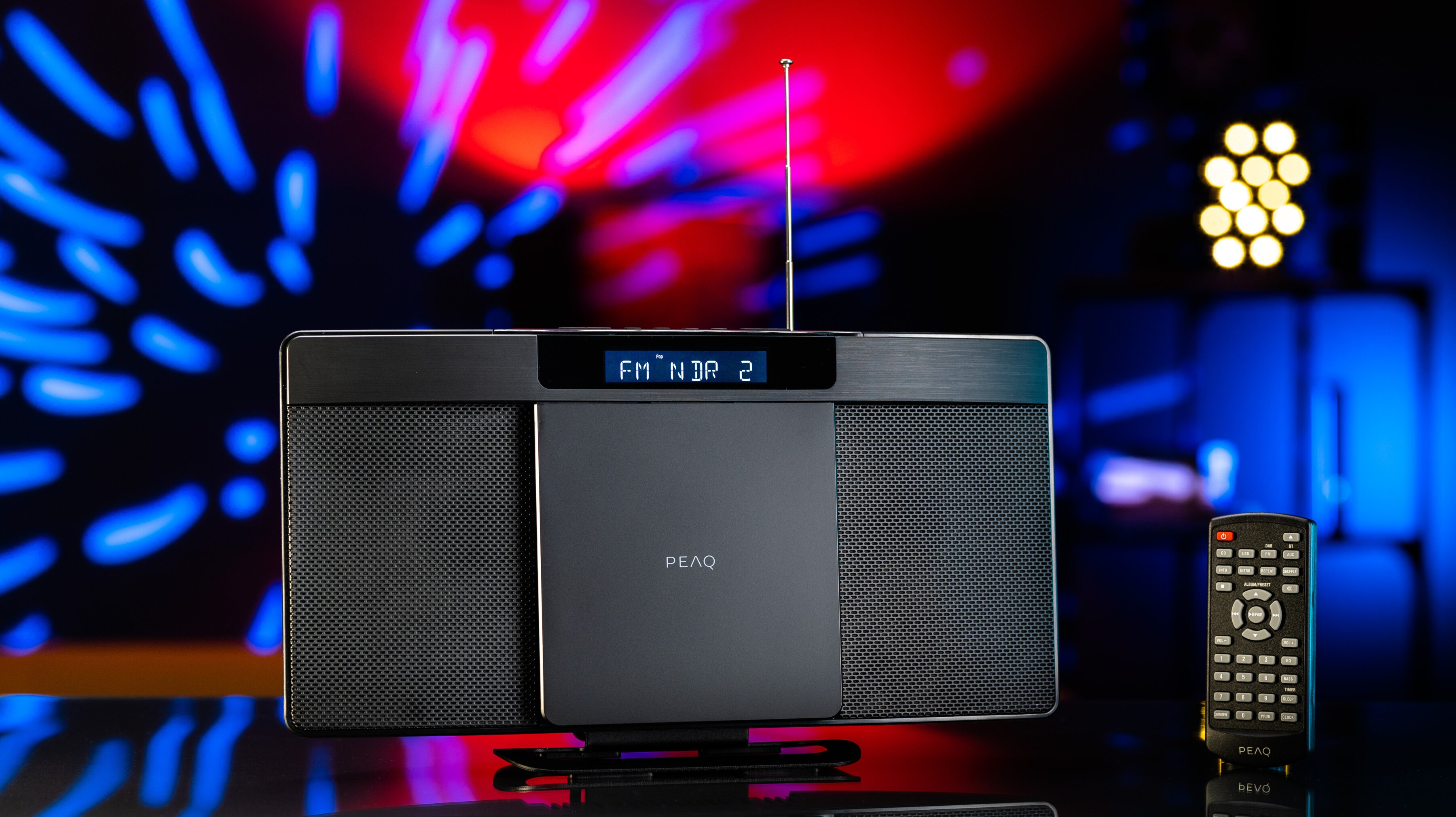 Radio nera con display e antenna, e un telecomando su uno sfondo sfocato.