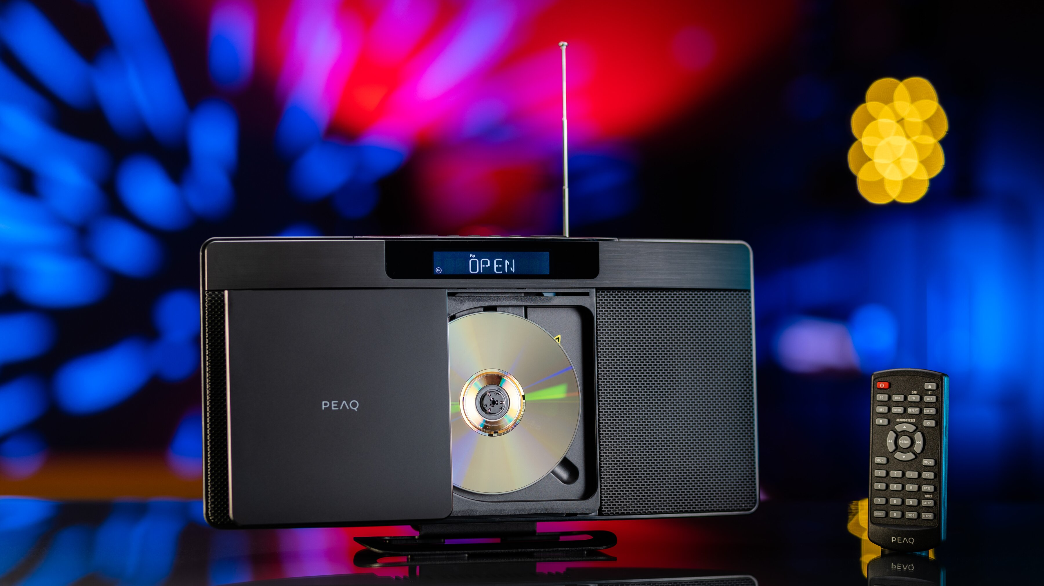 Stereo nero con lettore CD e telecomando. Vassoio CD aperto, sfondo luminoso.