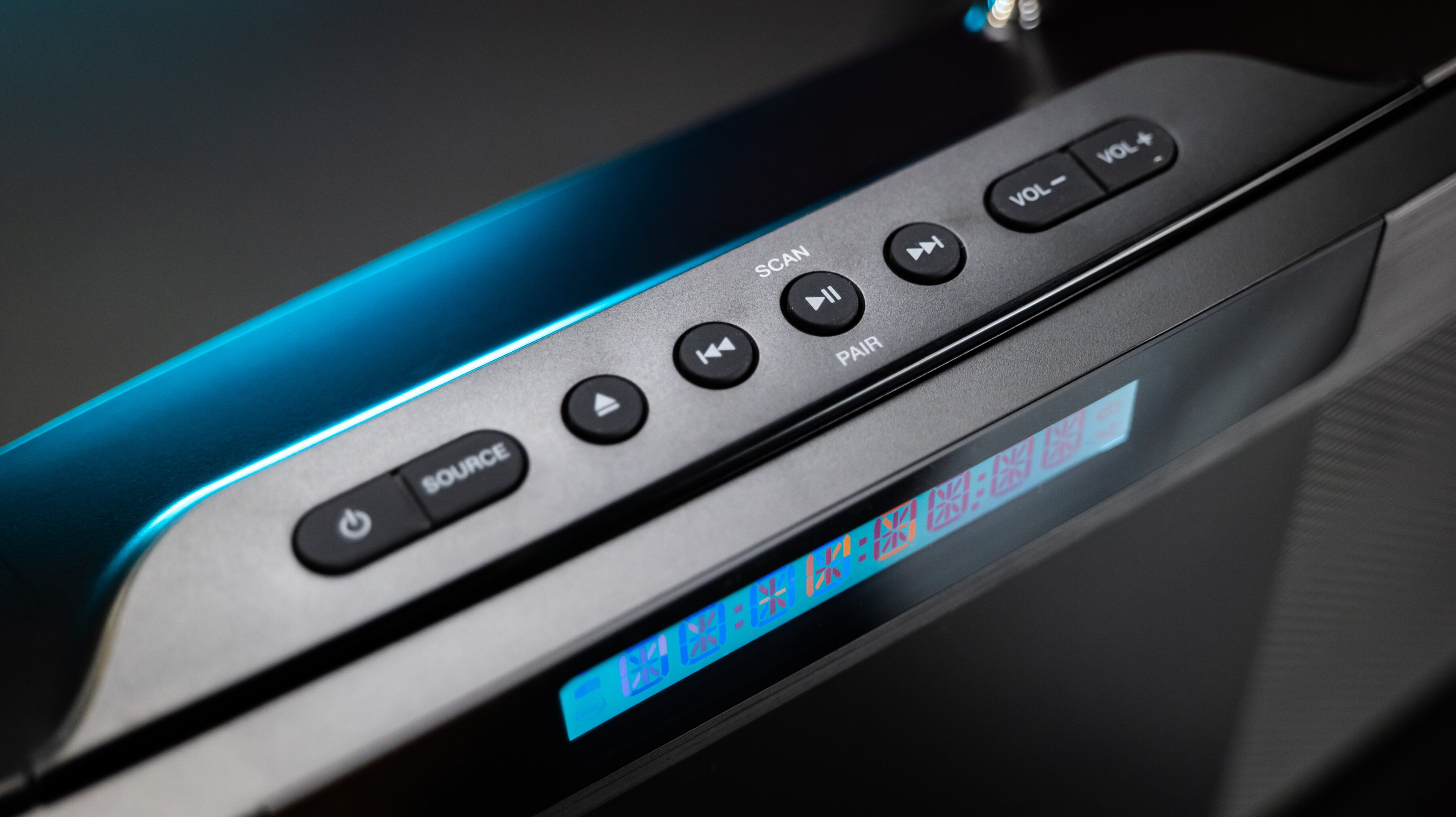 Primo piano del pannello di controllo di un lettore multimediale con pulsanti e un display blu.