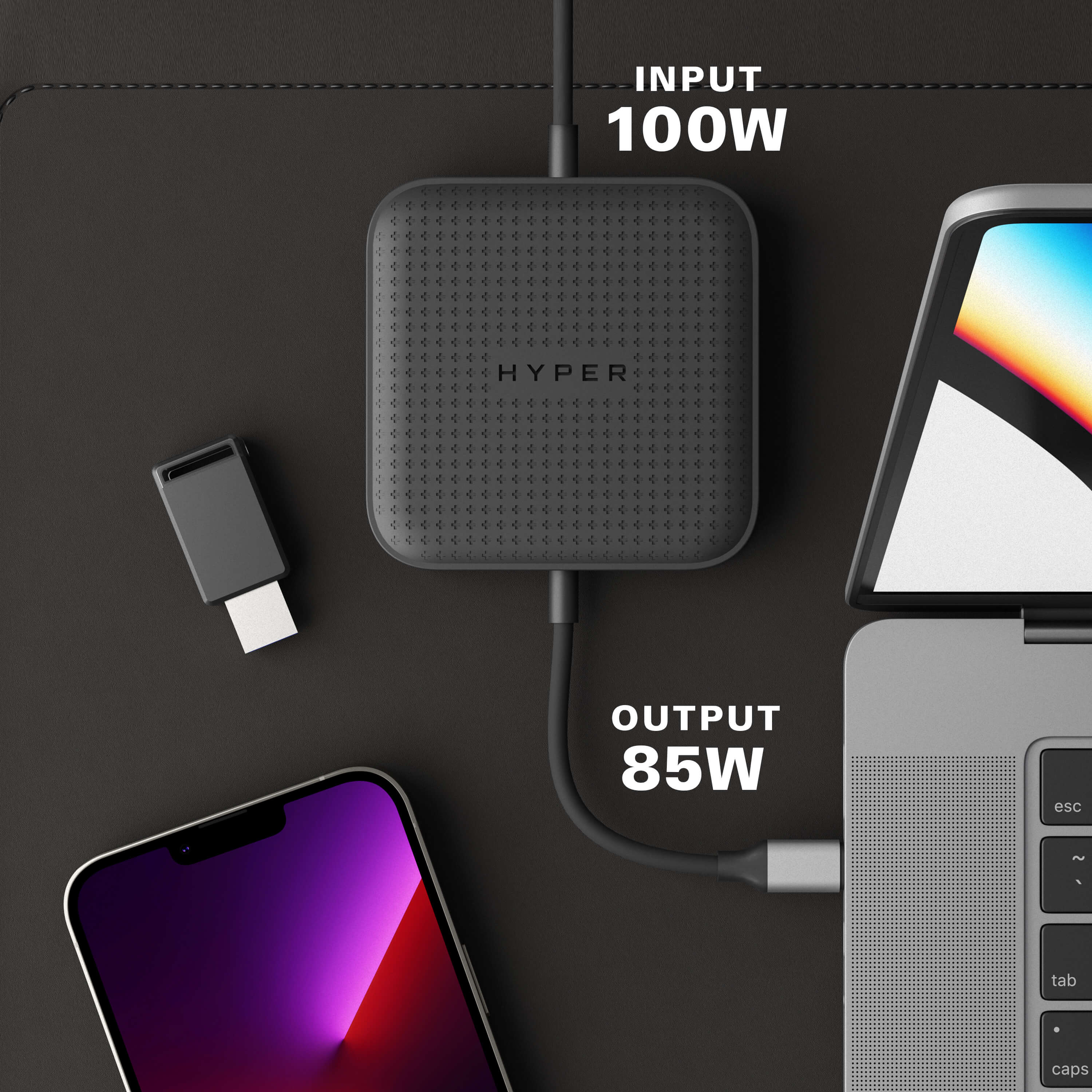 Concentrador de carga negro con texto 'HYPER' y dispositivos conectados: teléfono, portátil y adaptador USB.