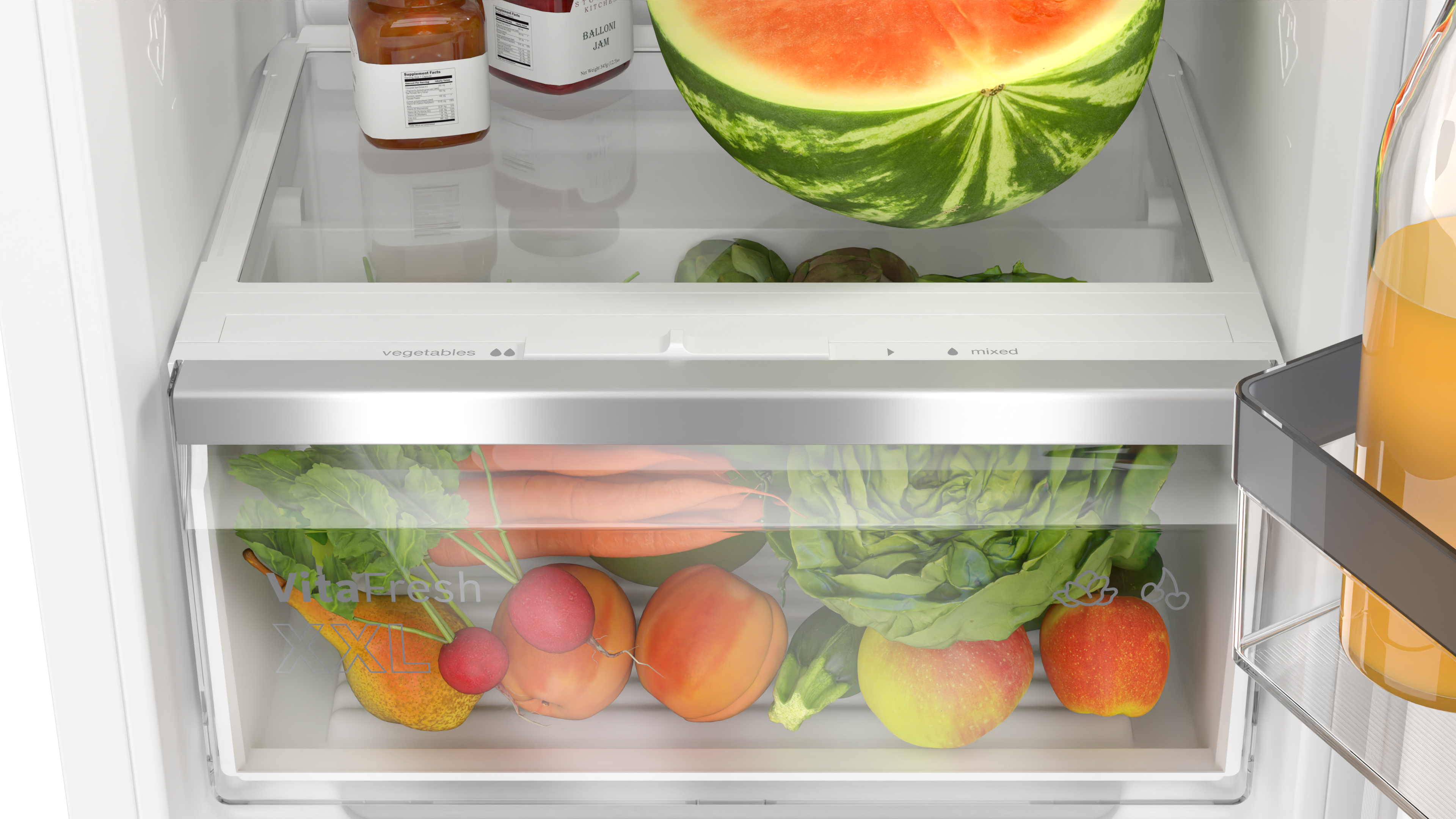Kühlschrank Schublade gefüllt mit Gemüse und Obst, mit einer Wassermelone oben drauf.