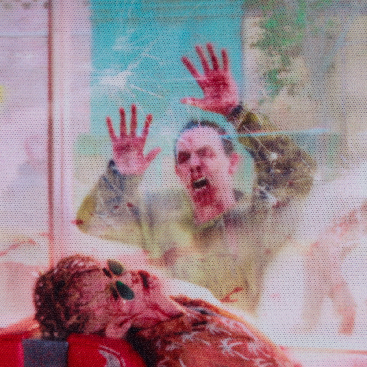 Zwei Personen hinter Glas, eine mit erhobenen Händen, die andere mit Blut.