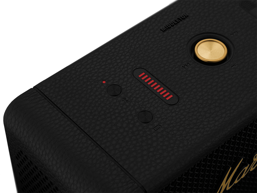 Close up of black Marshall speaker with red light and gold controls.